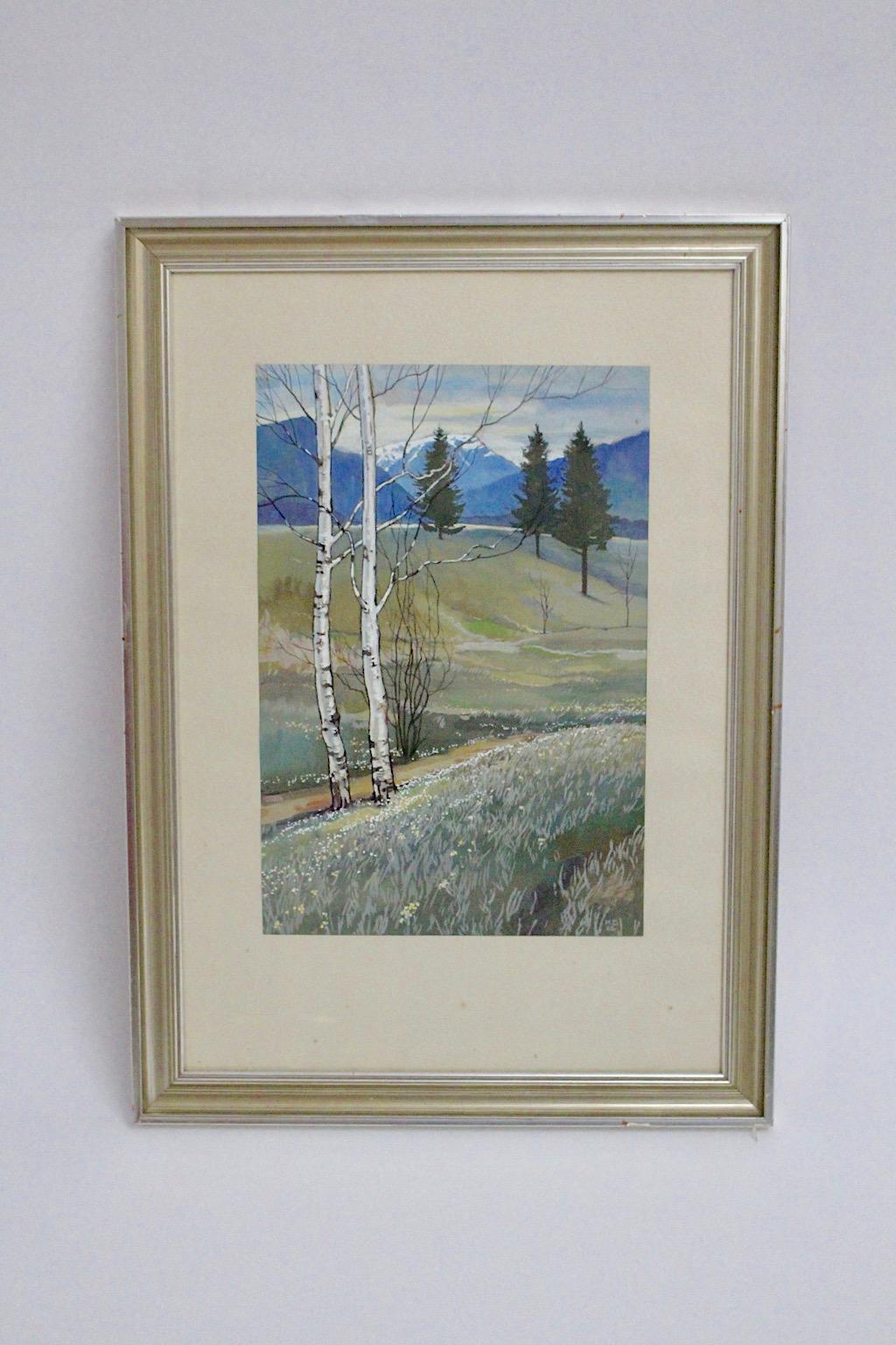 Mid-Century Modern vintage landscape painting with motif Schneeberg in Lower Austria in pastel tone color blue, grey, silver, green and white with watercolor on cardboard behind glass.
The painting is silver framed with an ivory colored passe -
