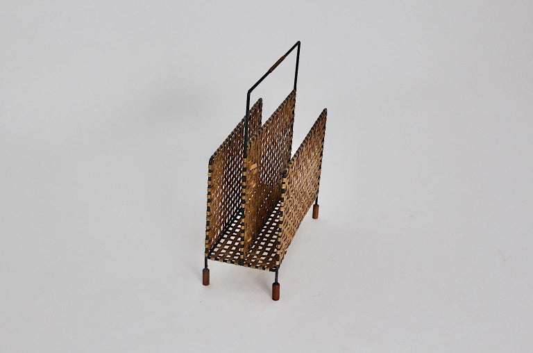  Mid-Century Modern vintage metal magazine rack or magazine stand, which was designed and made out in Austria, 1960.
While the metal frame was made of black lacquered metal, both side parts were made of woven mesh.
Four wooden sabots complete the