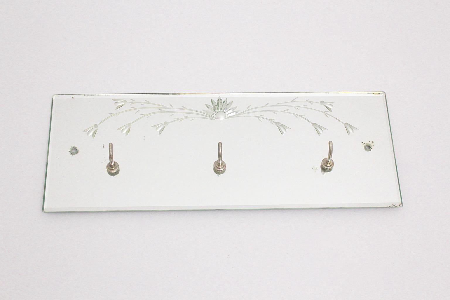 Mid-Century Modern vintage coat rack from mirror glass with etched flowers 1950s Italy.
An amazing board or rack from mirror with etched flower design and three metal hooks for towels, keys or coats. 
This mirror glass rack shows good condition with