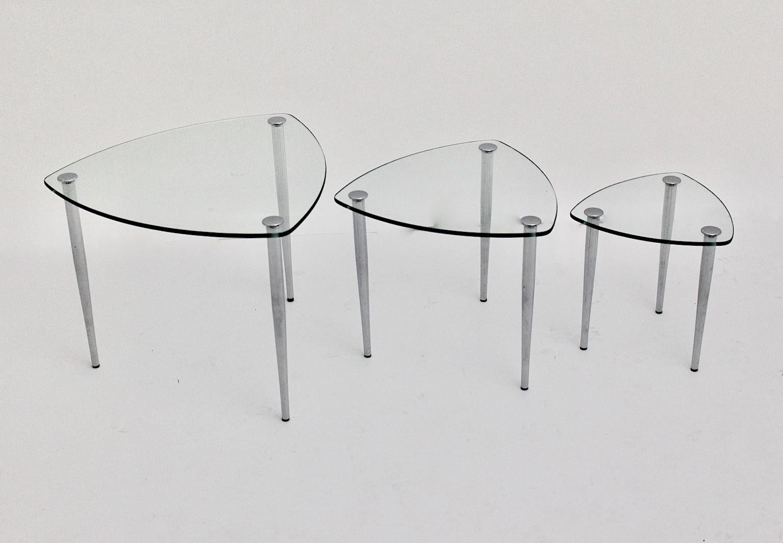 Mitte des Jahrhunderts Modern  drei Vintage-Nesting-Tische mit drei verchromten Füßen, die mit einer klaren Glasplatte verbunden sind. Die Füße sind auch leicht verschraubbar.
Auch die Tabellen zeigen drei Größen und eine Dreiecksform.
Entworfen und
