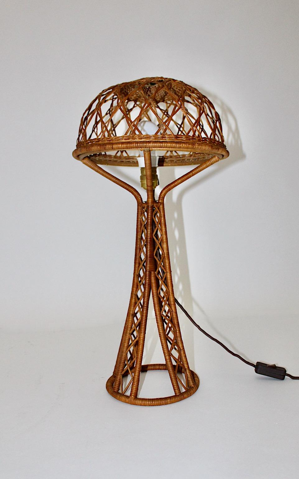 Mid Century Modern vintage organic table lamp Eiffel with mushroom like shade from rattan 1950s.
While the delicate lamp shade from rattan shows delicate rhomboid pattern the lamp base features an Eiffel like shape.
The organic modern rattan work
