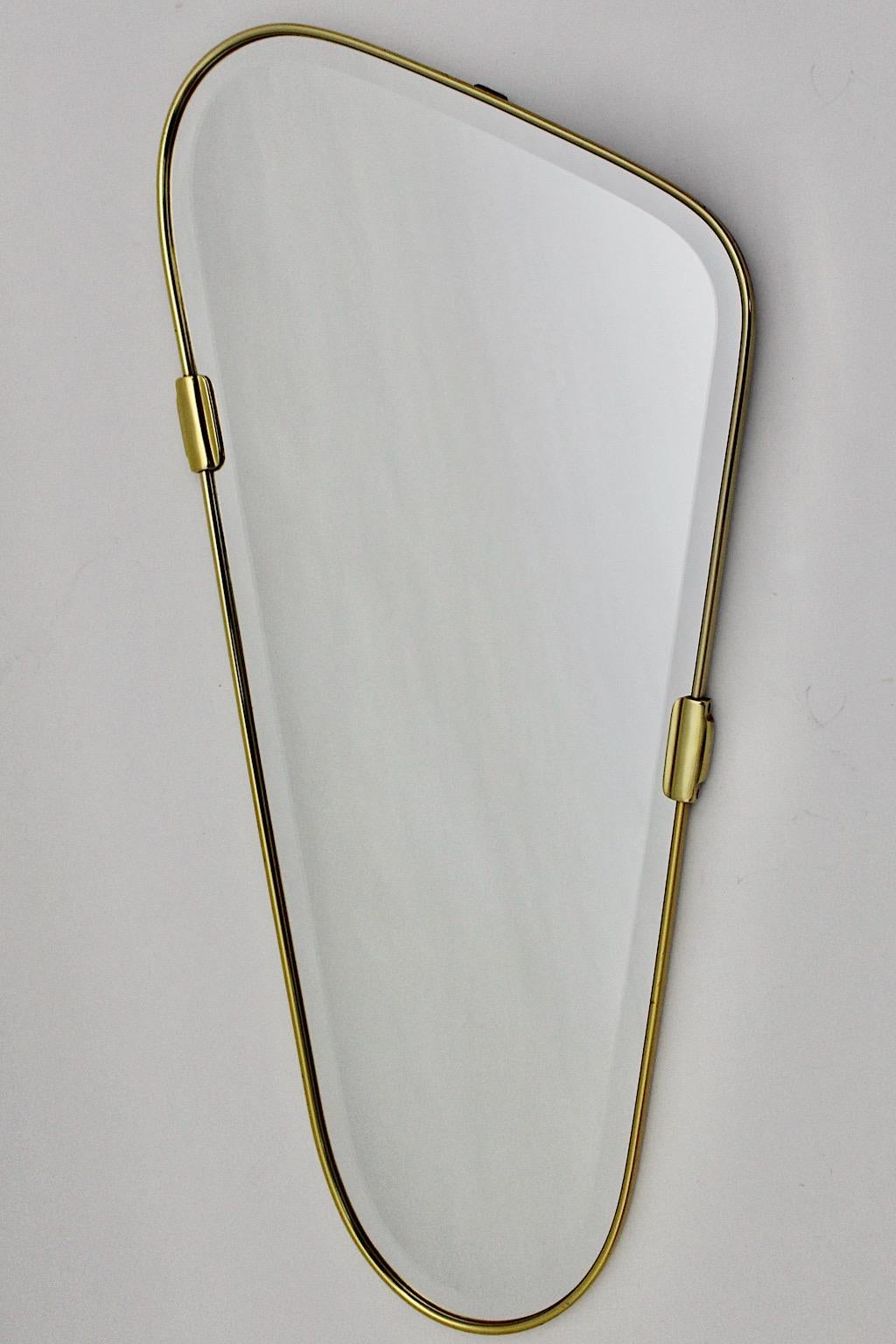 Mid Century Modern vintage oval wall mirror from brass and facetted mirror glass 1950s Italy.
Amazing wall mirror with thick solid brass frame and two brass clasps as decor, while the renewed mirror glass shows an elegant facetted high quality