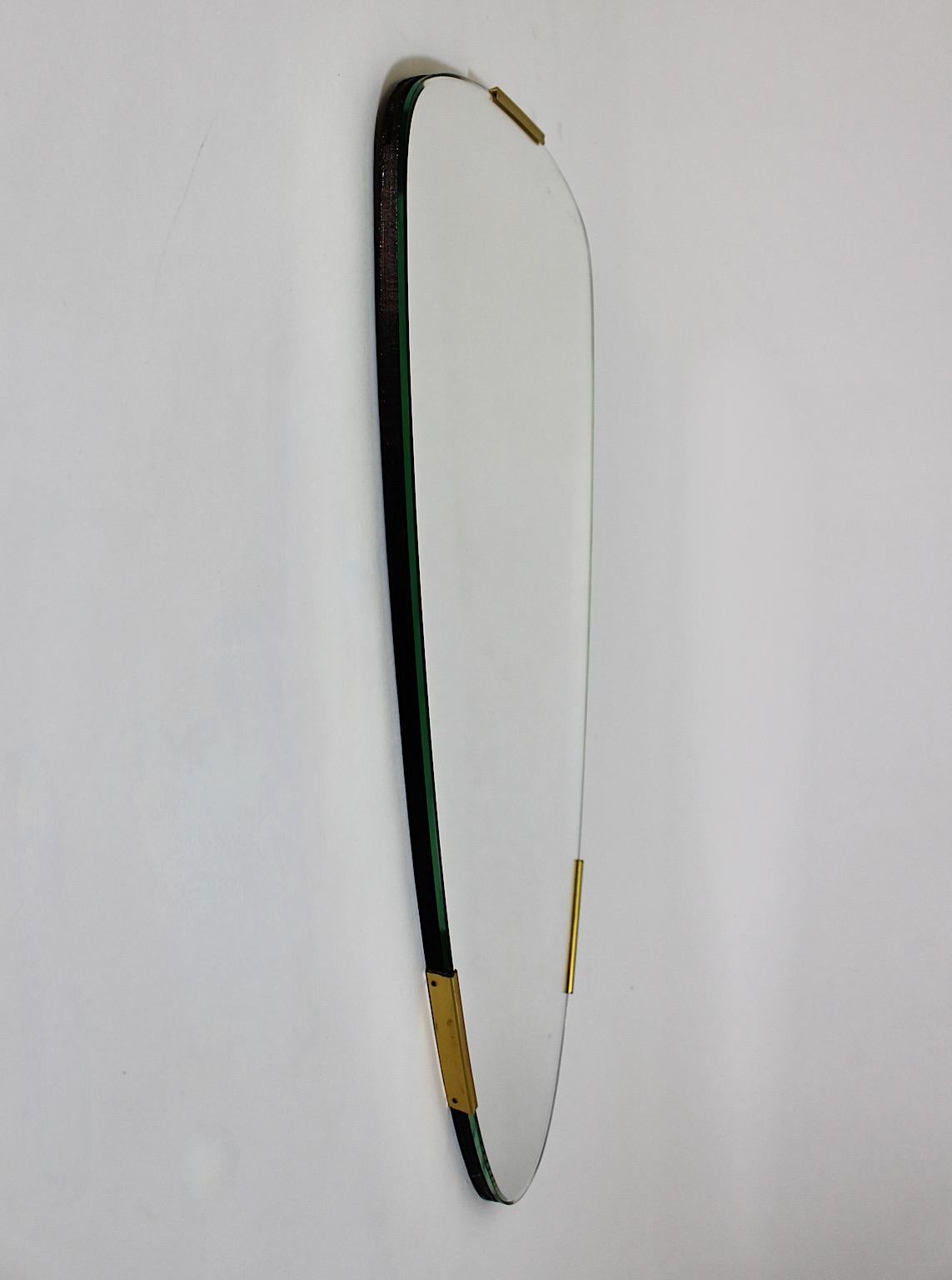 Mid Century Modern vintage conical like floor mirror or wall mirror frameless, but with three ( 3 ) brass clasps as detail, 1950s Italy.
A stunning frameless oval floor mirror shows facetted mirror glass and three brass clasps.
Backside one hook and