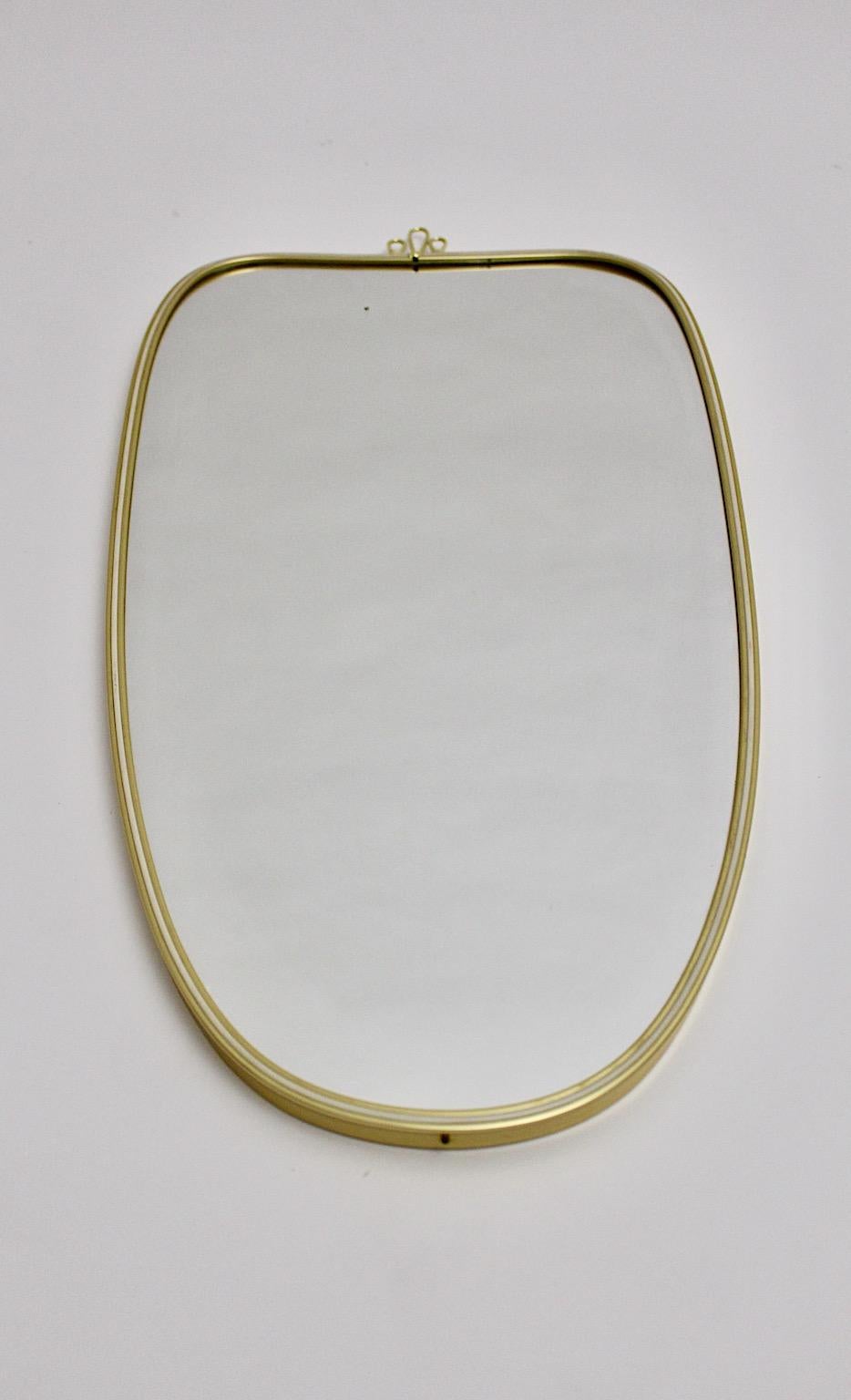 Modernist vintage oval wall mirror from mirror glass and golden metal Italy 1950s.
This amazing wall mirror shows an elegant oval shape with a small curved decor at the top.
The condition is good with signs of age and use. The mirror glass has a