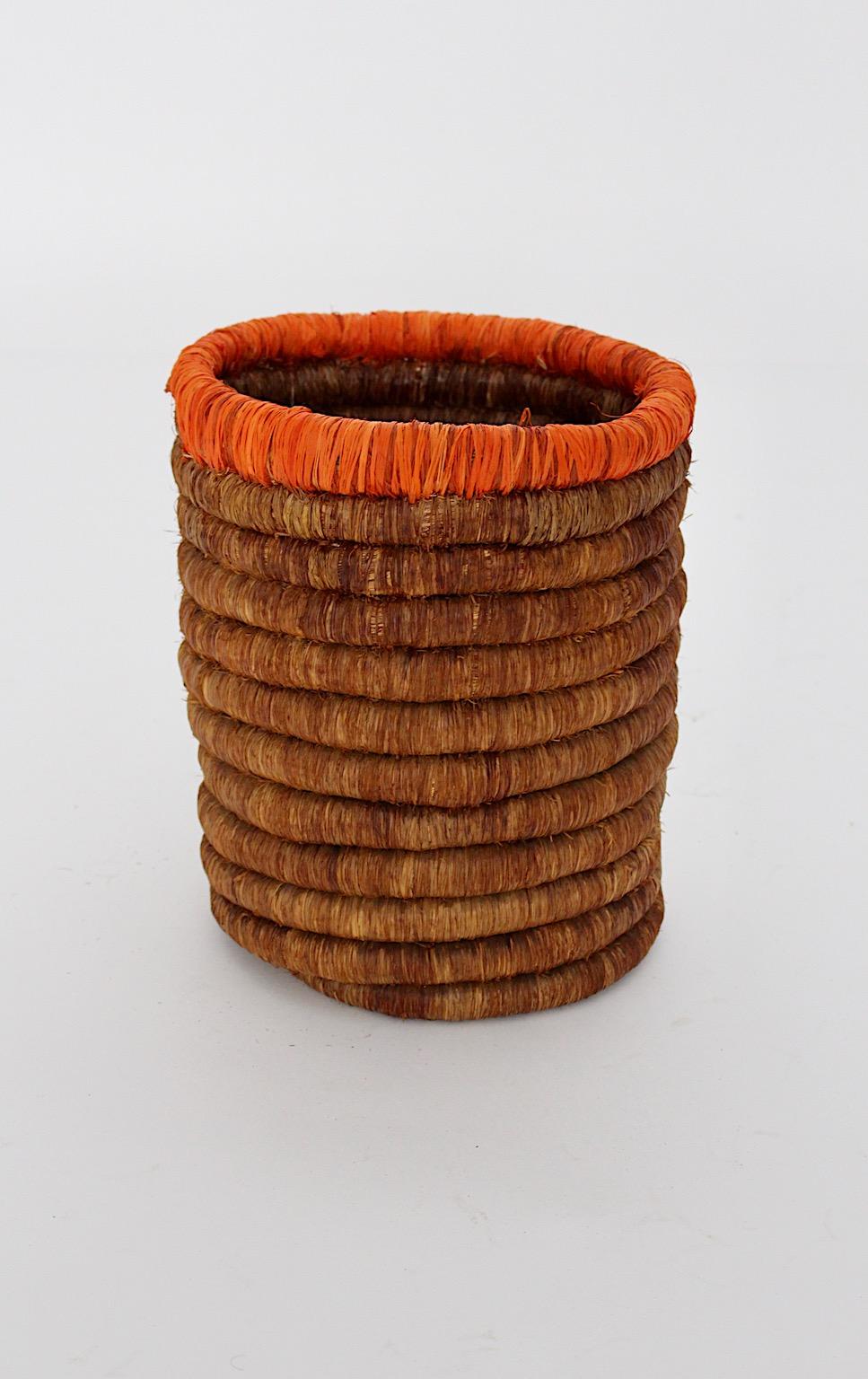 Mid Century Modern organic vintage basket or paper basket from raffia or sisal in brown and orange colors manufactured Austria 1950s.
The basket shows beautiful woven network in smooth warm colors.
We decided to cross 