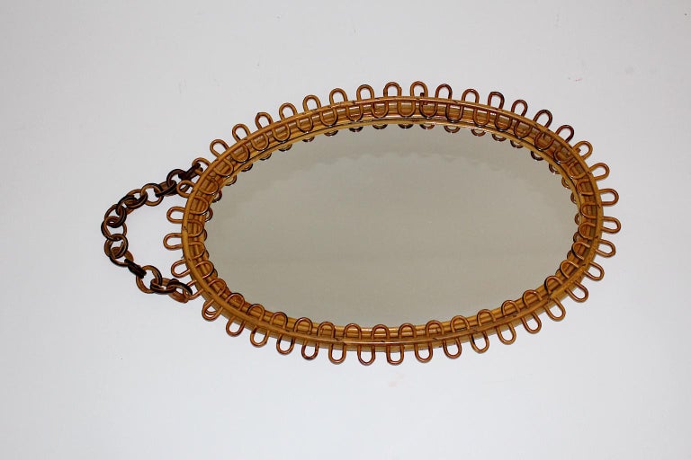 A Mid-Century Modern vintage sunburst wall mirror, which was made of rattan / wicker with curved sunbeams. Furthermore an original chain with approx. 7 cm length makes it easy to hang up the wall mirror with oval shape.
The wall mirror is carefully