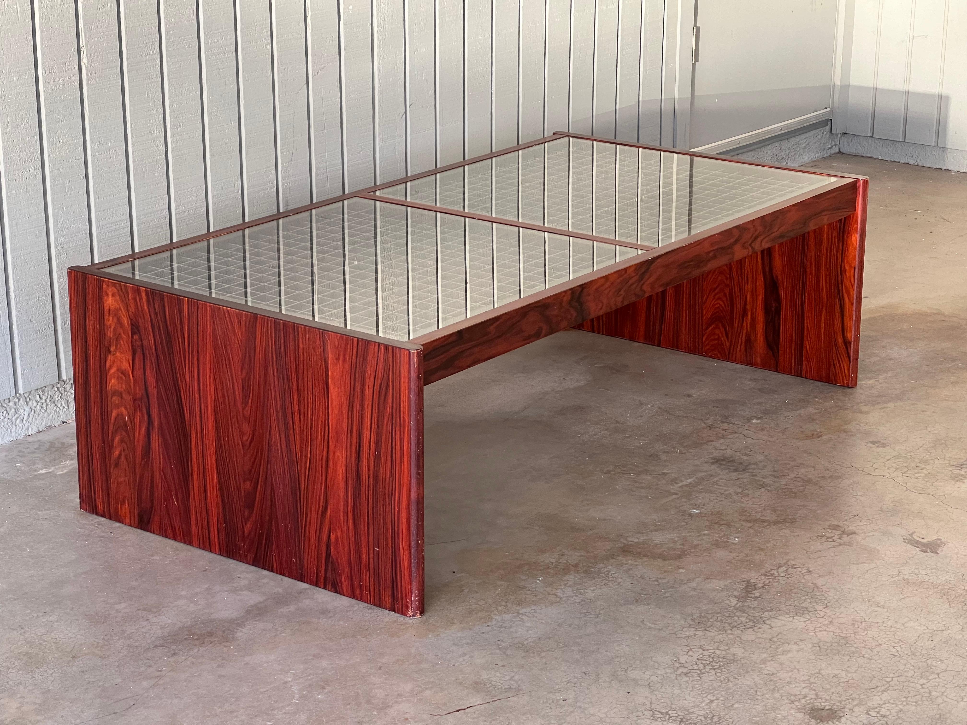 Danish rosewood and glass coffee table by Komfort, likely 1970s. Two pieces of glass cover a wood grid or lattice pattern. Labeled Made in Denmark. The rosewood has some amazing contrasting grain. It is very sturdy, a truly stunning piece. 55.5”