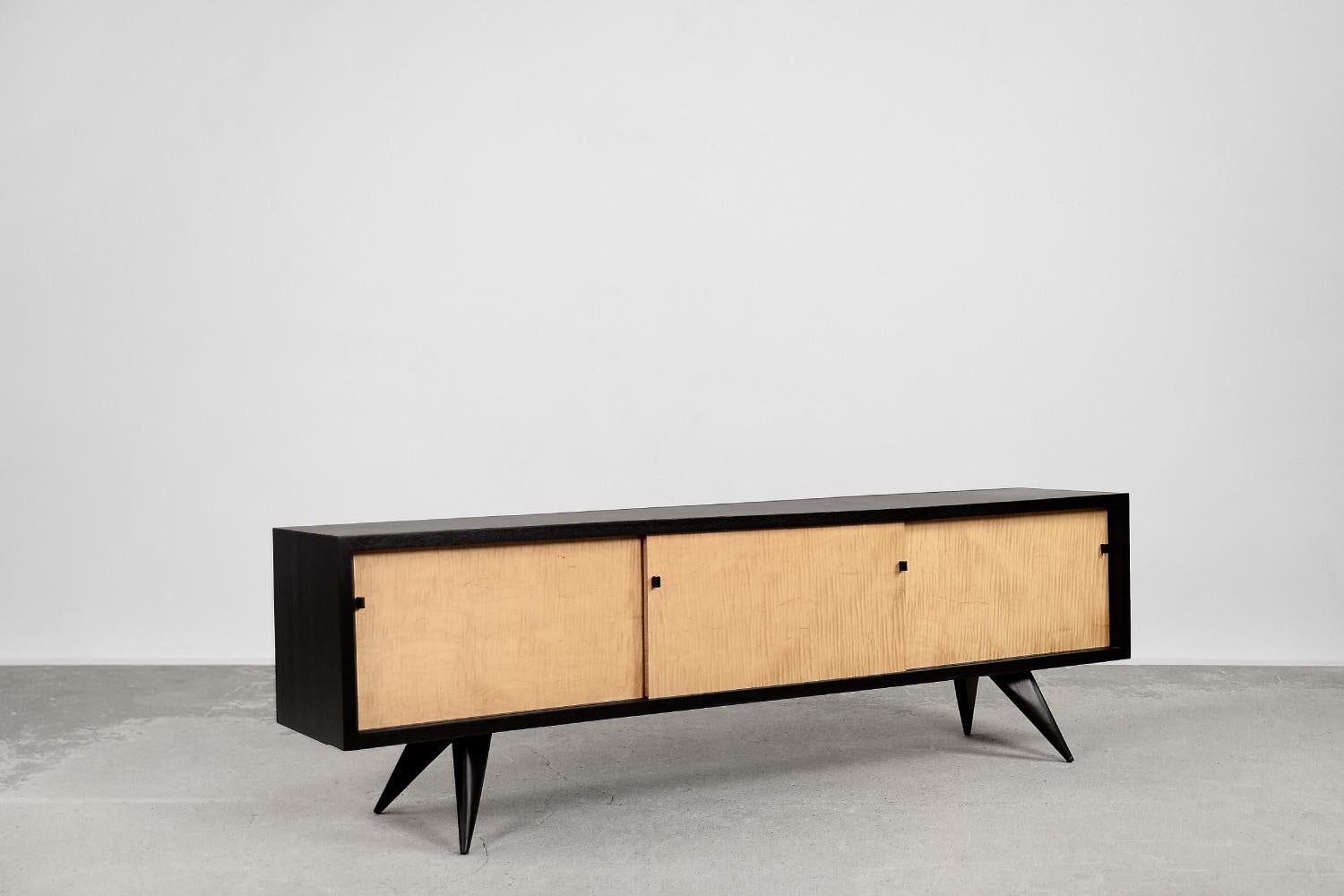 Ce buffet vintage moderniste du milieu du siècle a été fabriqué en Scandinavie dans les années 1960. La commode est fabriquée en bois de haute qualité à grain visible et laquée en noir. La façade est en bois d'érable, qui présente un aspect rare et