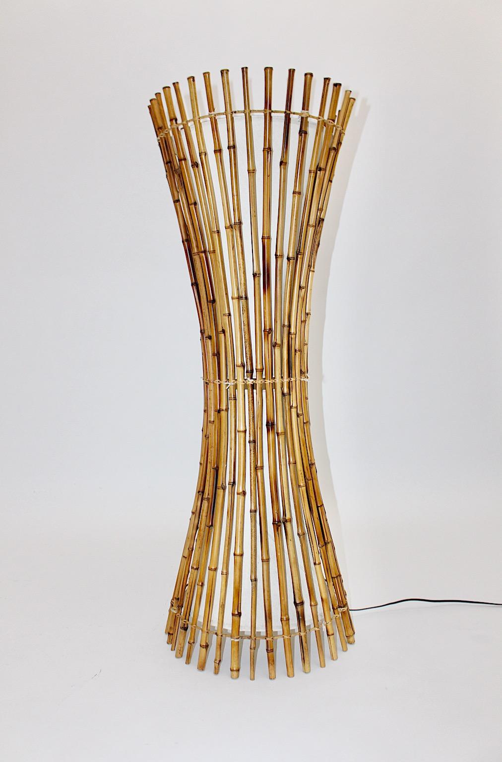 Mid-Century Modern vintage floor lamp shaped like a sheaf of rattan designed and executed 1970s Italy.
The organic shape of the sheaf of rattan shows many rattan sticks underlined with butter cream canvas fabric.
It lights with two E 27