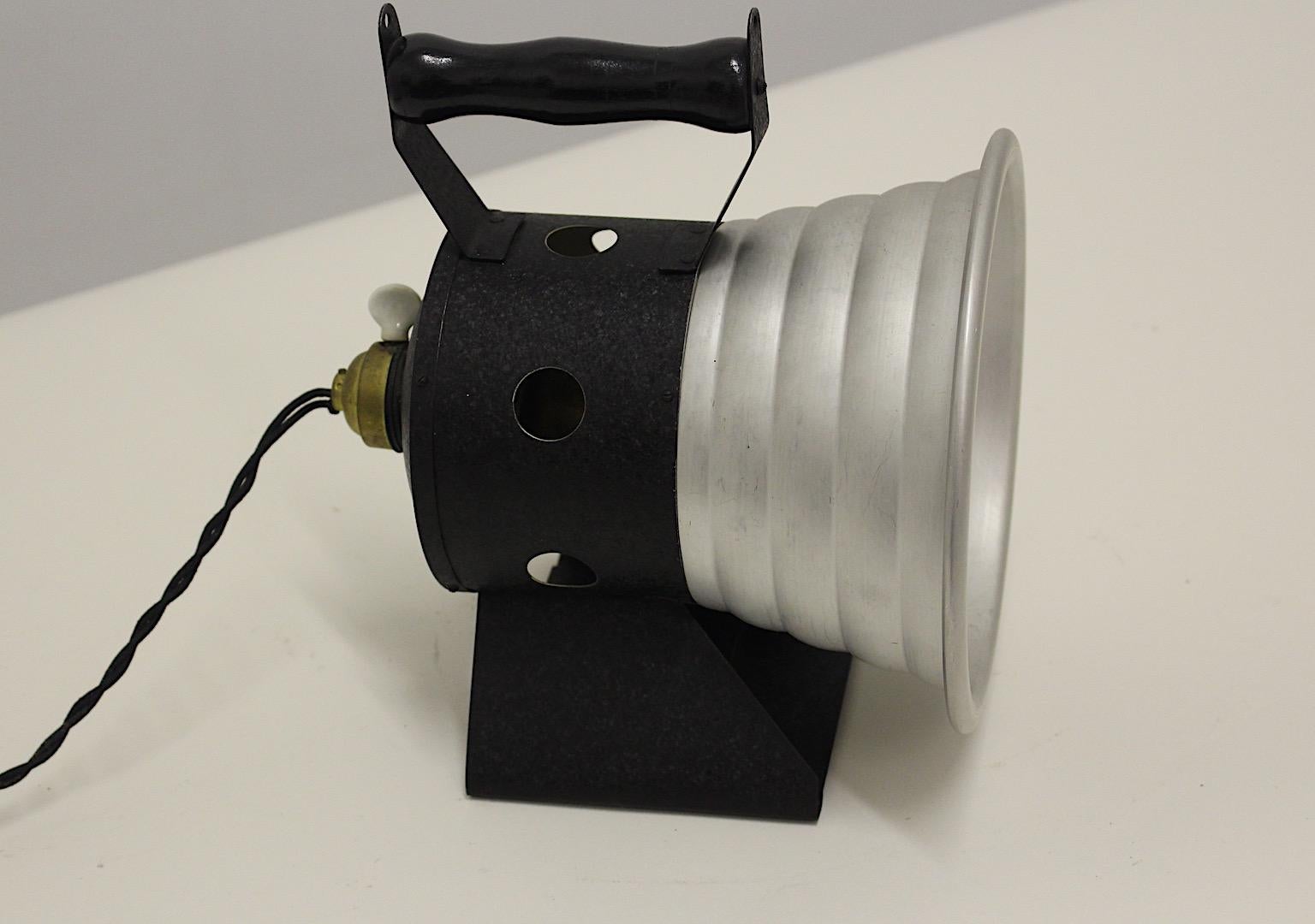 Mid Century Modern vintage table lamp or spotlight with handle 1940s.
A beautiful table lamp from aluminum, metal and a wooden handle to place it, wherever needed from the 1940s.
The table lamp shows an on/off switch at the E 27 socket and a