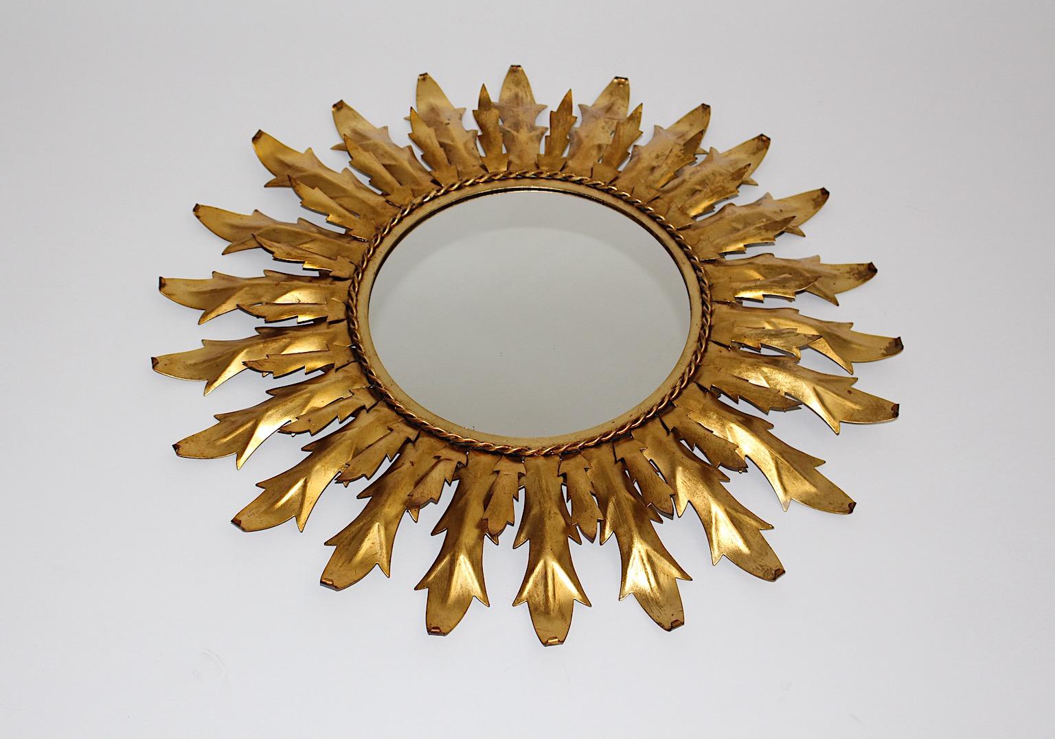 Mid Century Modern Vintage sunburst mirror or wall mirror from golden metal with curved leaves Italy, circa 1960.
A beautiful sunburst mirror or wall mirror from golden metal with leaves and a circular shaped mirror glass ( 28 cm ).
This wall mirror