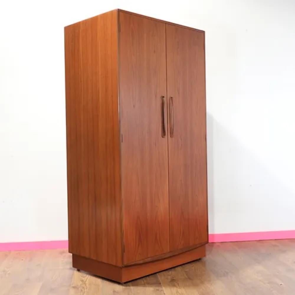 This stunning mid century modern vintage teak armoire by G Plan is a must-have for any lover of classic mid century furniture. Crafted from beautiful teak wood, this piece exudes timeless style and elegance. With a spacious interior featuring a