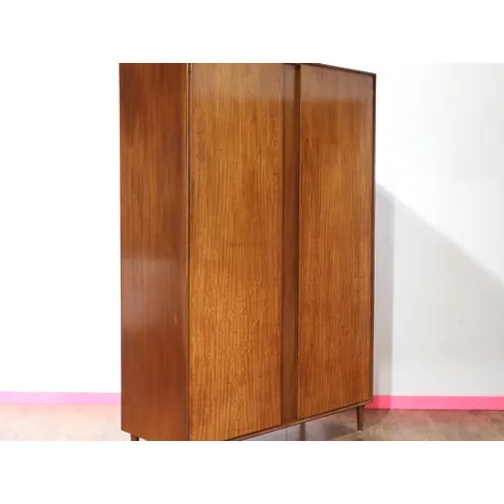 This vintage teak armoire wardrobe by Meredew is a stunning example of mid century modern design. Crafted with high quality teak wood, this piece exudes a timeless elegance that is sure to elevate any bedroom or living space. With plenty of storage