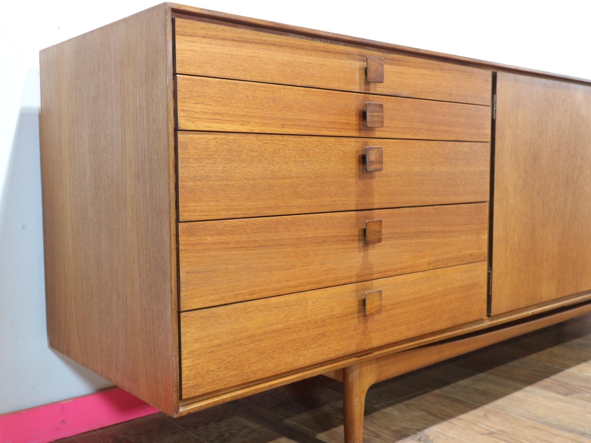 Discover the elegance of this stunning Kofod Larsen G Plan credenza at Mid Century Traders. With its beautiful handles and wonderful grain, this vintage teak masterpiece exudes timeless sophistication. Boasting fantastic storage, it perfectly