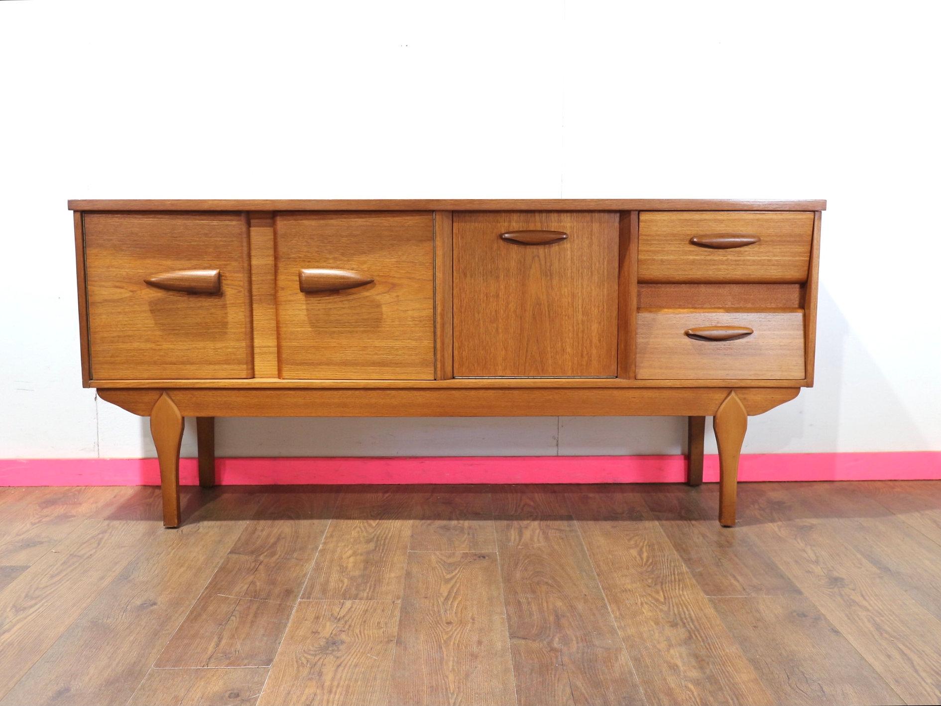 Scopri l'eleganza senza tempo della nostra credenza in teak vintage Mid Century Modern del rinomato produttore di mobili britannico Jentique. Questa splendida credenza combina lo stile danese con una sapiente lavorazione artigianale. Compatto ma con