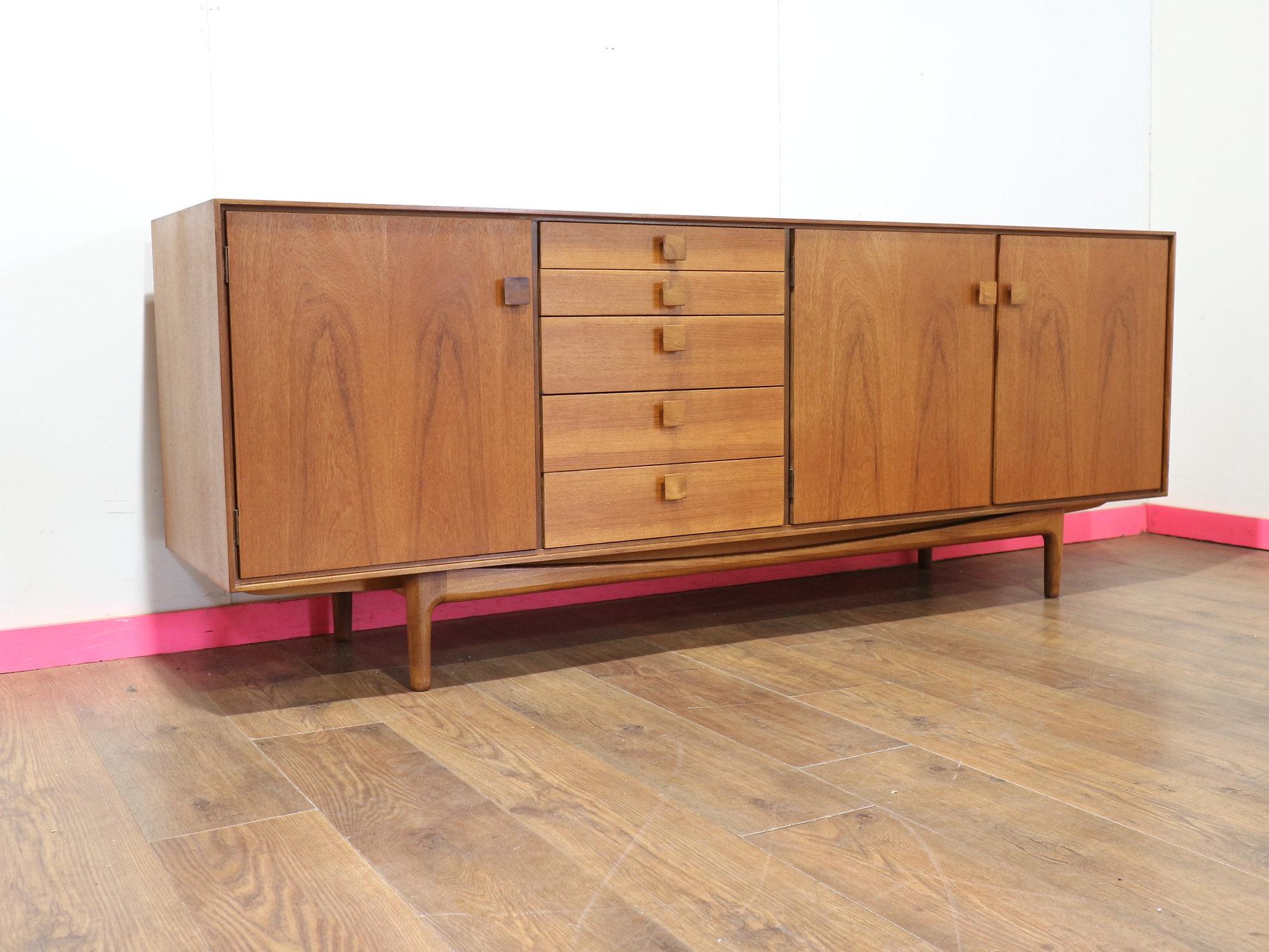 Designed by Kofod Larsen and part of the Danish G Plan range, this stunning Mid Century Modern Vintage Teak Credenza Sideboard offers fantastic storage with a touch of elegance. The meticulously crafted rosewood handles add a refined detail that