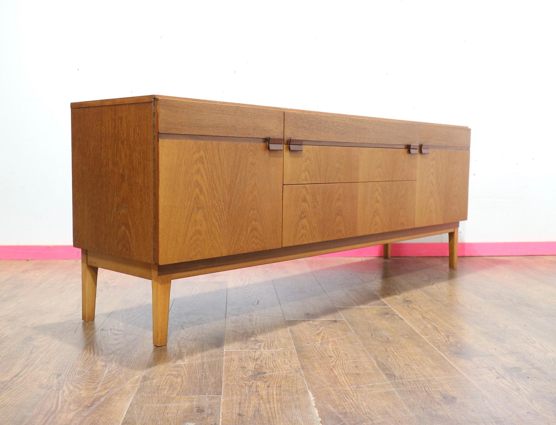 Discover the timeless elegance of this stunning credenza by British furniture maker Nathan. This exquisite Mid Century Modern Vintage Teak Credenza Sideboard, inspired by Danish style design, features a gorgeous grain and sculpted handles, making it