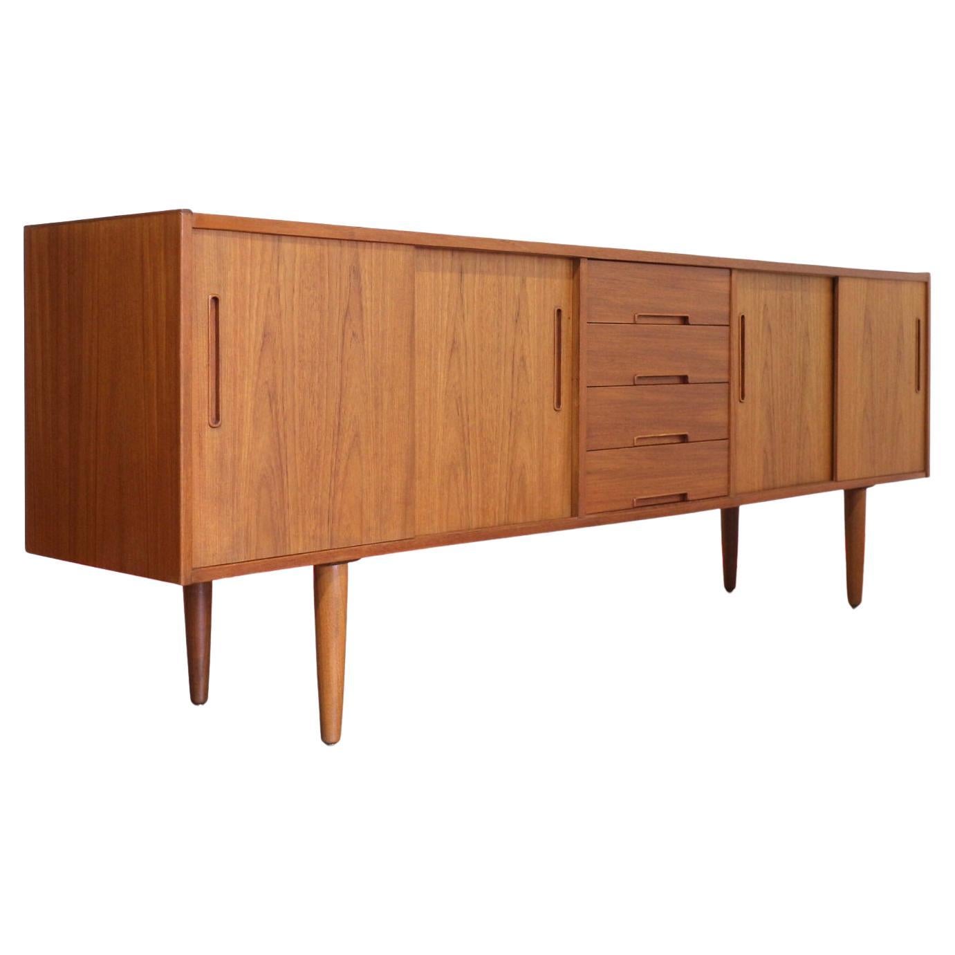 Eleva il tuo spazio abitativo con questa splendida credenza in teak vintage del Mid Century Modern Nils Jonsson Troed, disponibile in esclusiva da Mid Century Traders. Questo elegante pezzo combina un'ottima conservazione con il marchio di fabbrica