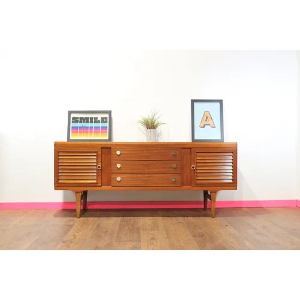 This stunning Mid Century Modern Vintage Teak Credenza Sideboard by Younger is the perfect addition to any mid century furniture collection. Crafted from teak by the renowned British furniture maker Younger, this credenza exudes the sleek and