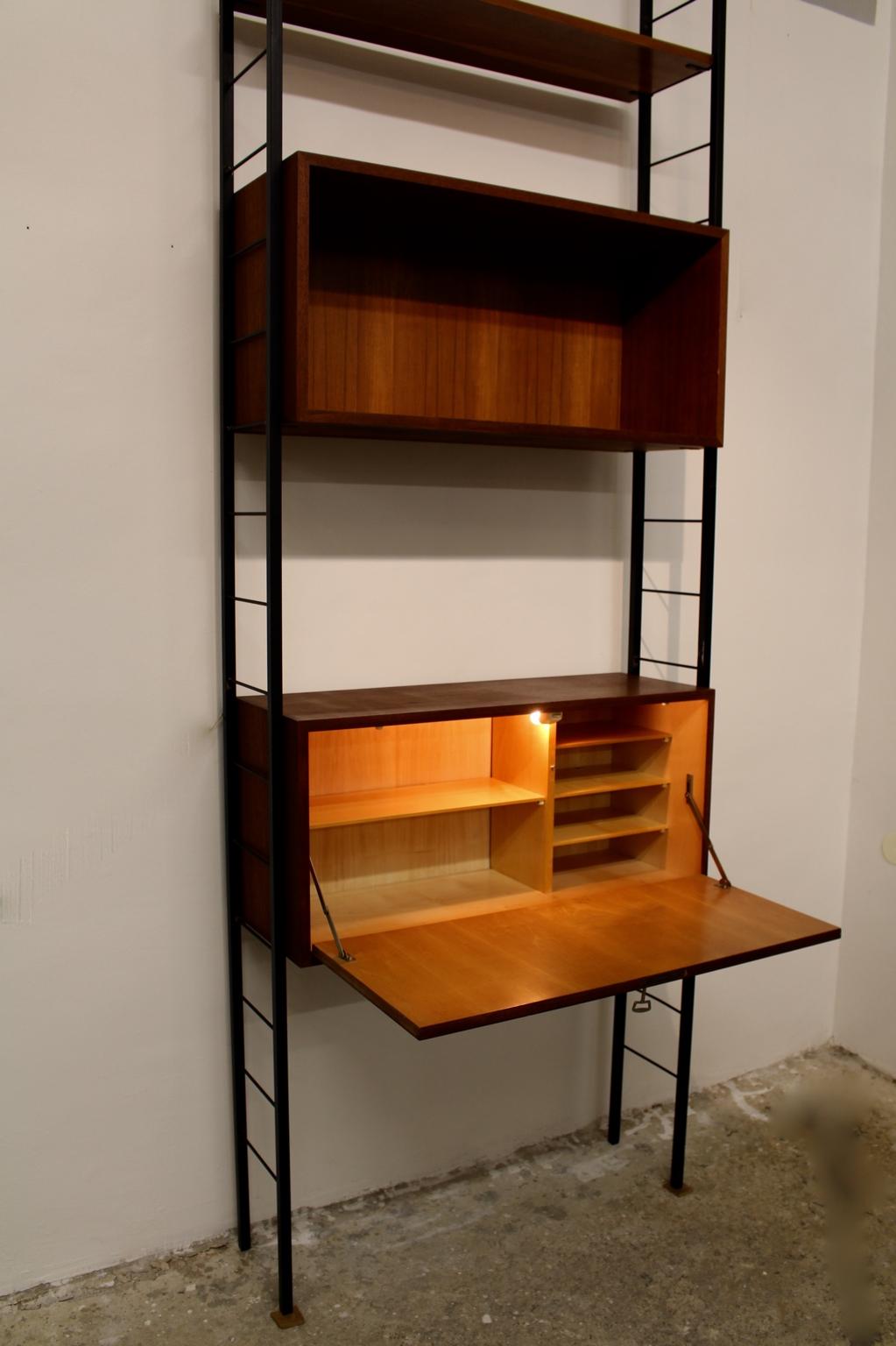 The presented vintage teak ladder string shelf consists of two black lacquered ladder elements, which are holding a lockable writing desk with lighting, two boards and one book storage. It is worth to mentioned that you are able to choose the height