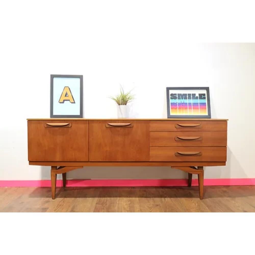 Introducing the Mid Century Modern Vintage Teak Sideboard Credenza by Beautility - a wonderful example of stylish mid century furniture. This stand out piece features beautifully sculpted legs that set it apart from the rest, adding a touch of