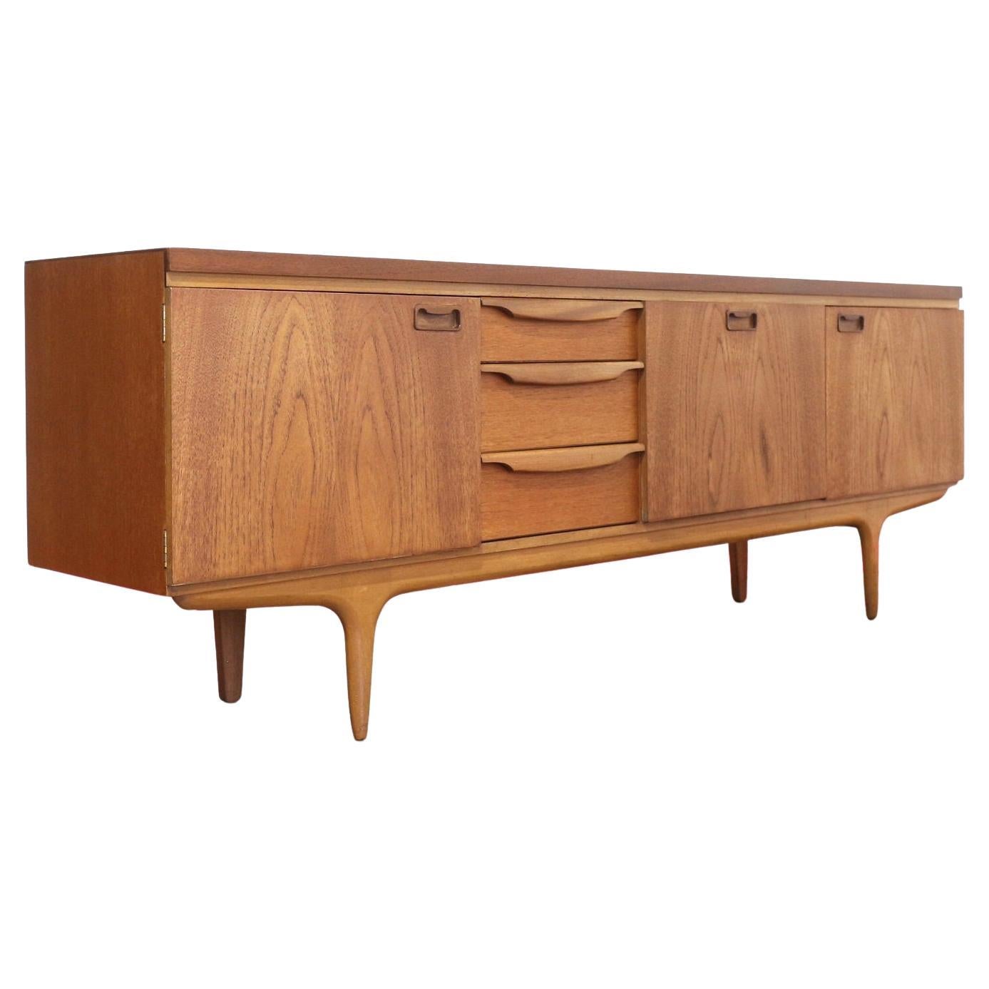 Discover the impeccable fusion of form and function with this beautiful credenza by renowned British furniture maker Greaves and Thomas. Exemplifying Danish style, this mid-century modern vintage teak sideboard offers great storage to keep your