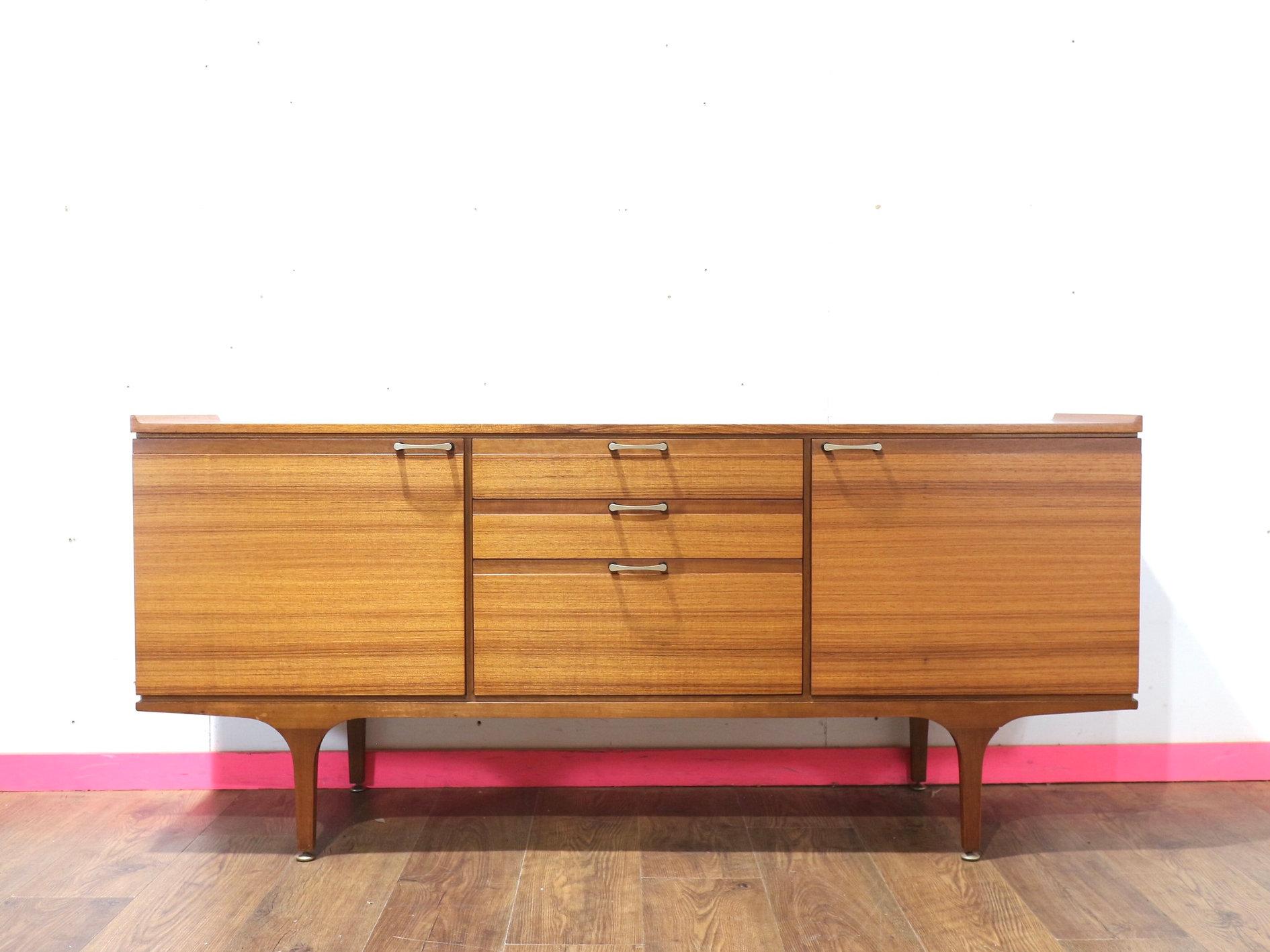 Elevate your space with this gorgeous mid century credenza by renowned furniture maker Meredew. Featuring fantastic wood grain and great storage, this teak sideboard is a stunning example of Danish style craftsmanship. At Mid Century Traders, we