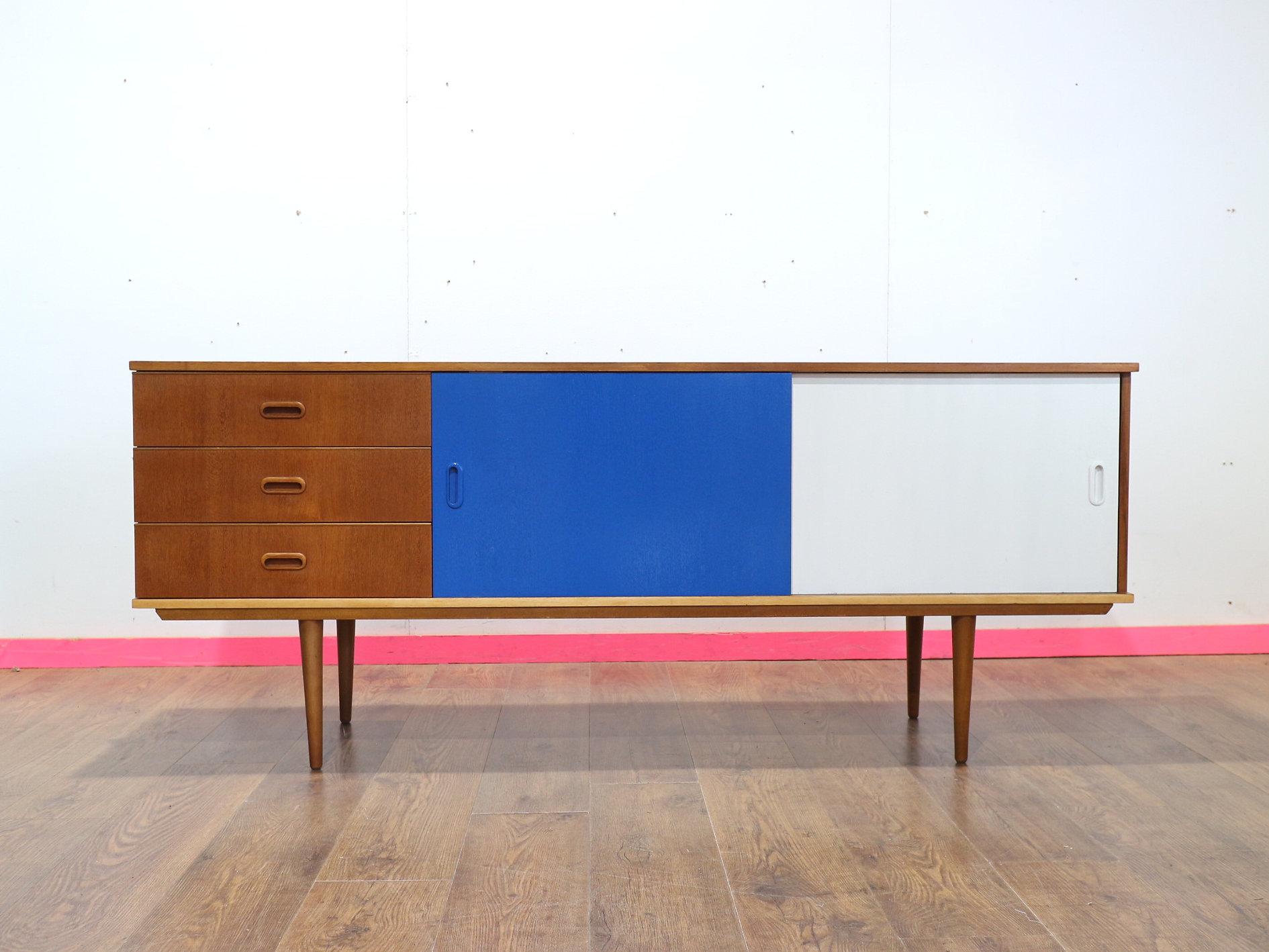 Discover the stunning Mid Century credenza by renowned British furniture maker Nathan at Mid Century Traders. This exquisite piece boasts elegant sliding doors colored blue and white, epitomizing the timeless charm of Mid Century Modern Style.