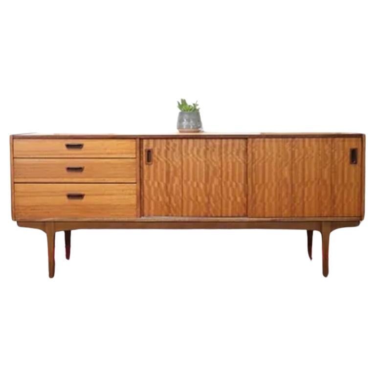 This Mid Century Modern Vintage Teak Sideboard Credenza by Nathan is a fabulous piece made by the renowned British furniture maker. This elegant credenza is a perfect example of Mid Century Style, with its stunning grain and stylish inset handles.