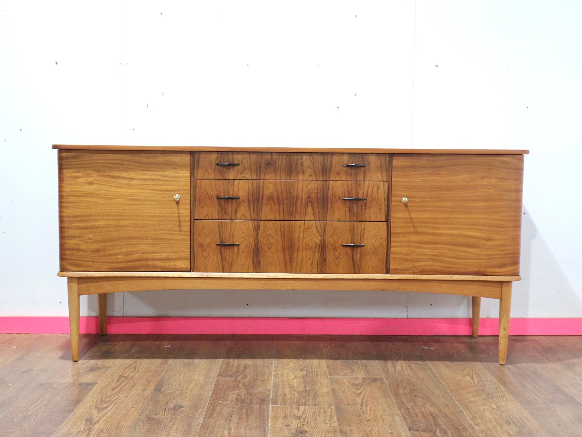 A stunning mid century modern sideboard by renowned British furniture maker Wrighton. Beautiful grain in the wood and fantastic curved doors add timeless elegance to any space. Ideal for design enthusiasts, this piece reflects the quality and