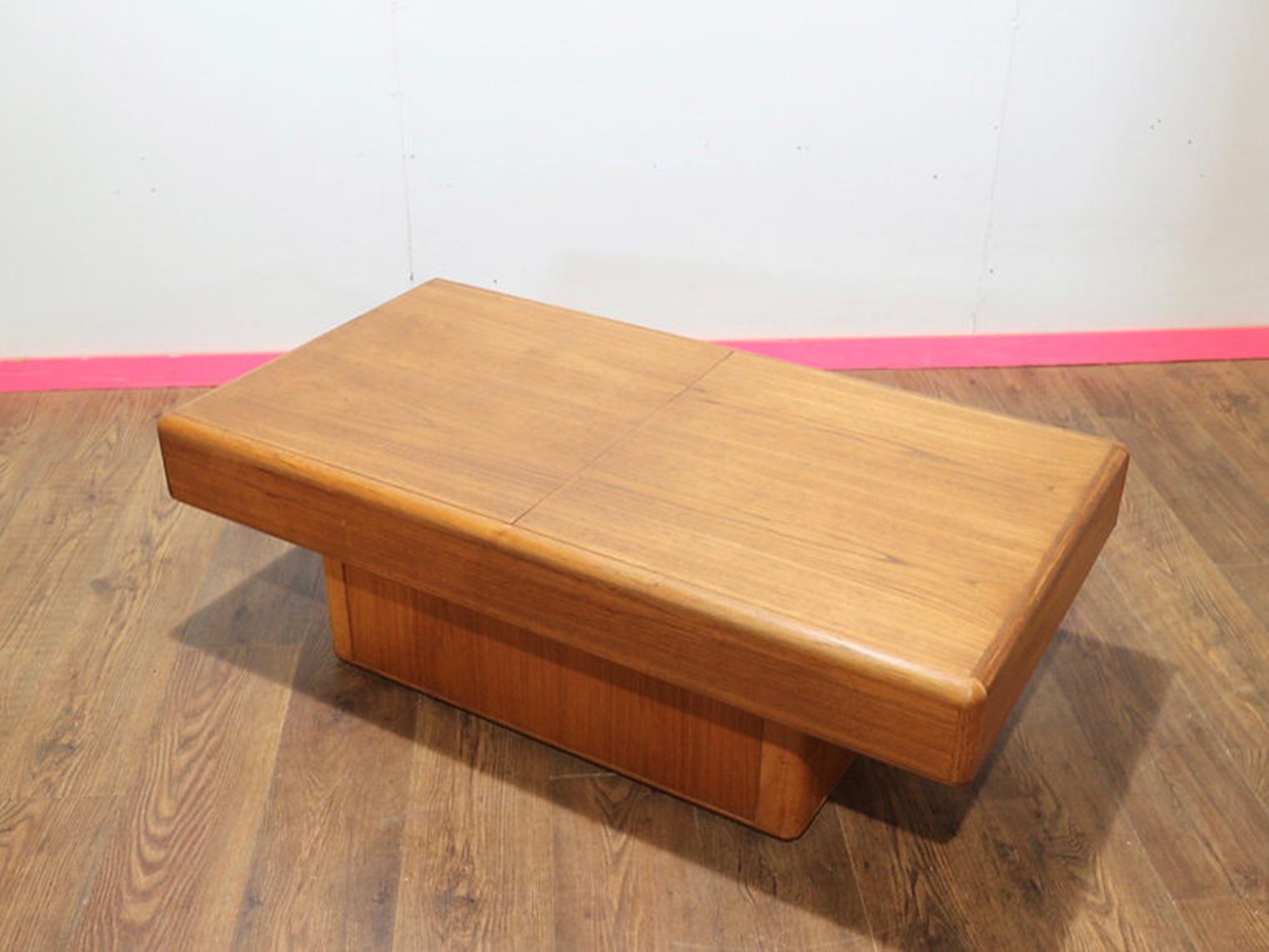 A gorgeous Danish Coffee table by renowned furniture maker Dyrlund awaits you at Mid Century Traders. This beautiful table, crafted from rich teak, features a hidden compartment that can be accessed by sliding open the tabletop, providing both style