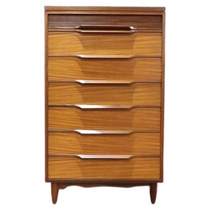 This stunning White and Newton tallboy dresser is by the British brand White & Newton of Portsmouth. This set of drawers is made from a grainy teak and feature a top reeded drawer front and lovely angled grab handles. The unit is made up of seven