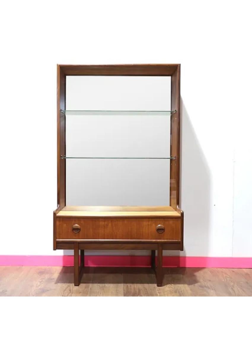 This display cabinet, crafted by Turnidge of London, made in a teak veneer structure complemented by sturdy afromosia handles and legs. It features a spacious glass sliding door cupboard with adjustable shelves and two convenient lower drawers