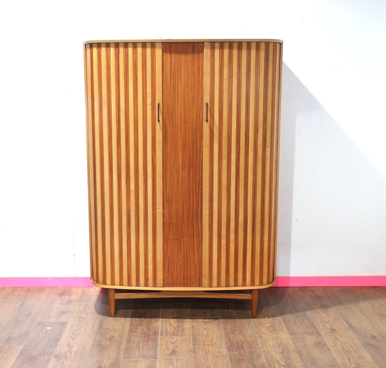 Scopri l'epitome dell'eleganza della metà del secolo scorso con il nostro splendido Armoire Ausinsuite vintage con porta a tamburo in teak. Caratterizzato da ante a tamburo ricurve, questo armadio mette in risalto le sfumature di legno a contrasto,
