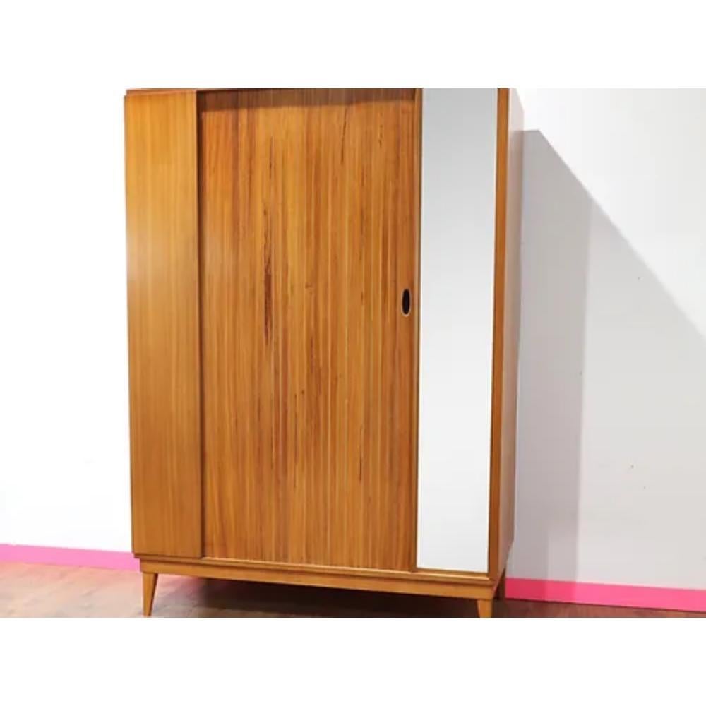 Introducing this Mid Century Modern Vintage Teak Tripple Armoire with Tambour Door by Austinsuite, a stunning addition to any mid century furniture collection. This British-made piece is a true representation of the craftsmanship and design of the