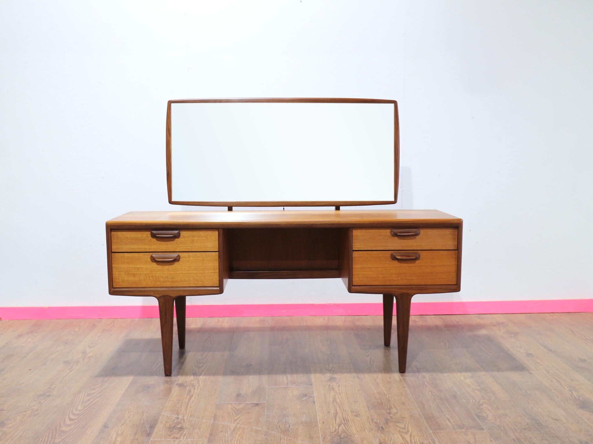 Entdecken Sie die Anziehungskraft der Mid Century Eleganz mit dem Mid Century Modern Vintage Teak Vanity Dresser Desk von Younger. Dieser wunderschöne Waschtischschrank des angesehenen britischen Möbelherstellers Younger besticht durch seinen Stil