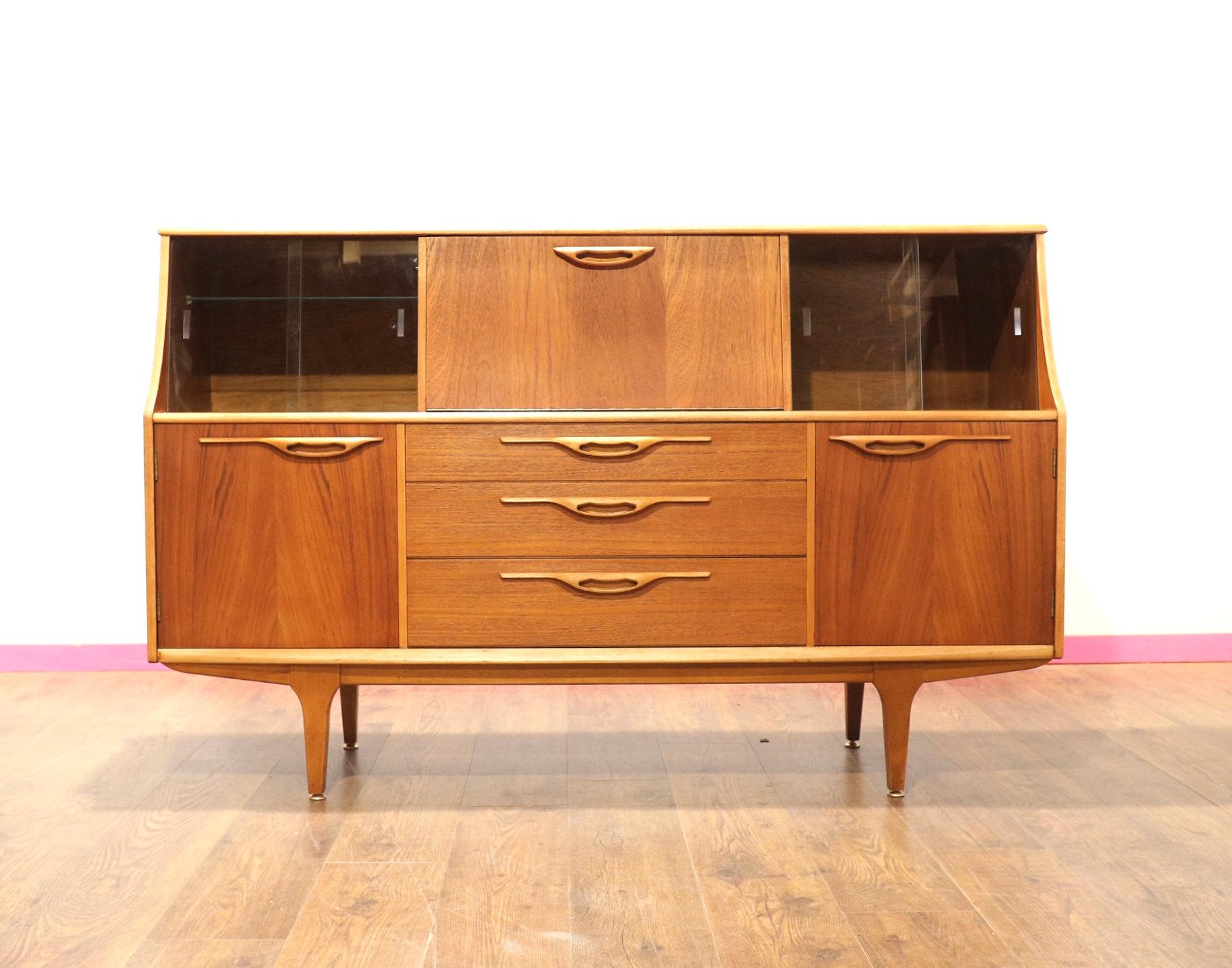A brilliant teak credenza by British furniture maker Jentique, this Mid Century Modern Vintage Teak Buffet Credenza Sideboard exudes timeless elegance and functionality. Crafted in a classic Danish style, it offers great storage with various
