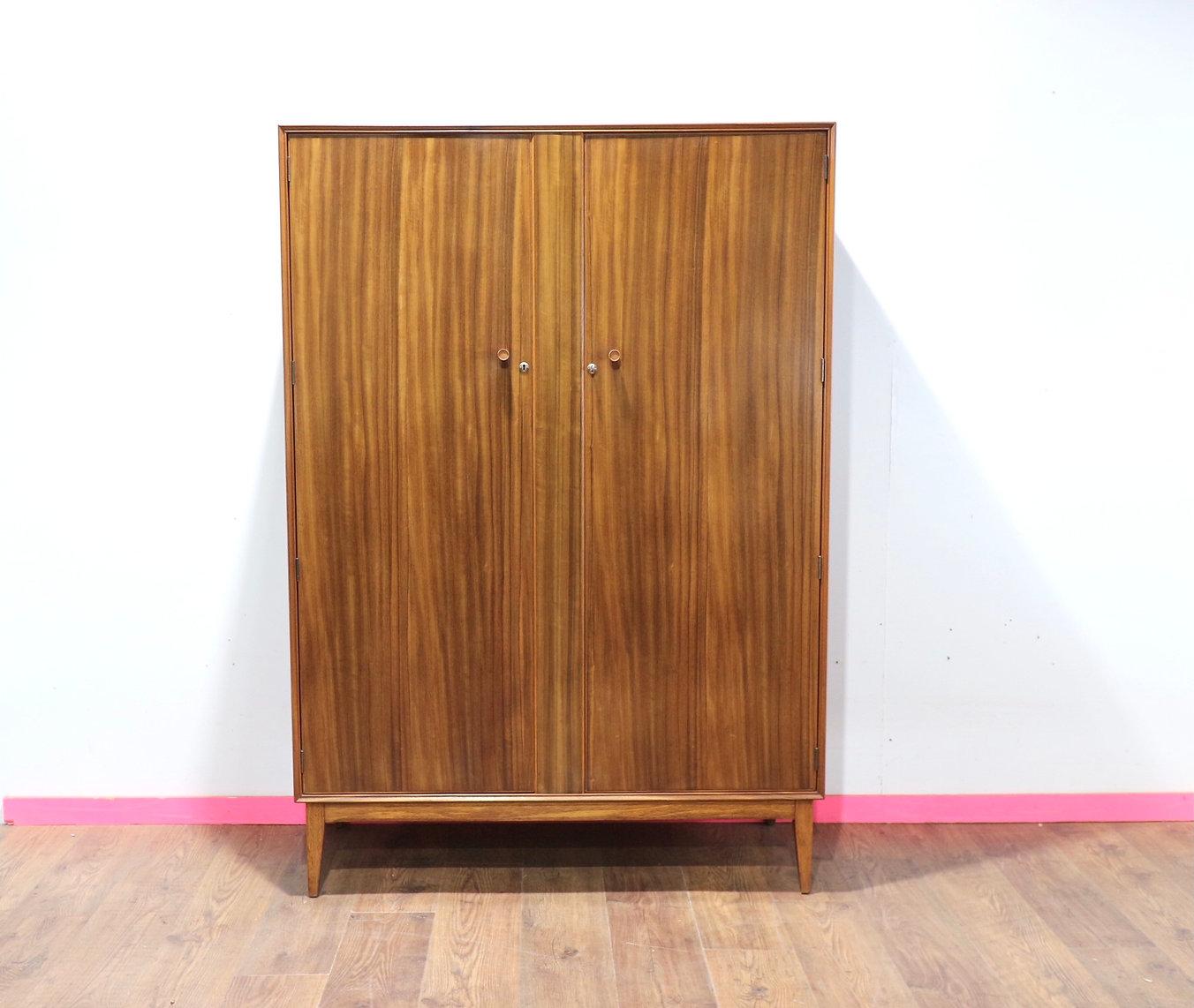 Elevate your bedroom aesthetic with the Mid Century Modern Vintage Triple Armoire by Alfred Cox, available at Mid Century Traders. This large mid century wardrobe, meticulously crafted from walnut, boasts great storage and a beautiful grain,