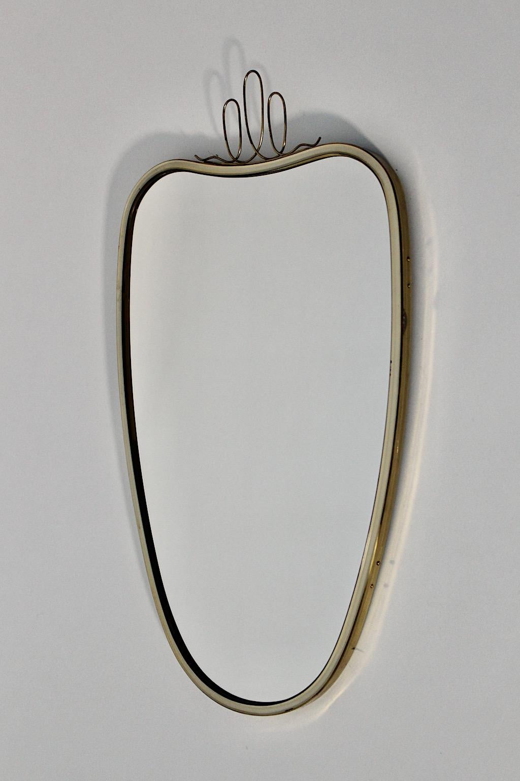 Mid-Century Modern Vintage Wandspiegel weißer Metallrahmen mit Messing Details Herz wie 1950er Wien.
Ein atemberaubender Vintage-Wandspiegel, herzförmig gerahmt aus weißem Metall mit 3 zarten Schleifen aus Messing und Spiegelglas.
Während das