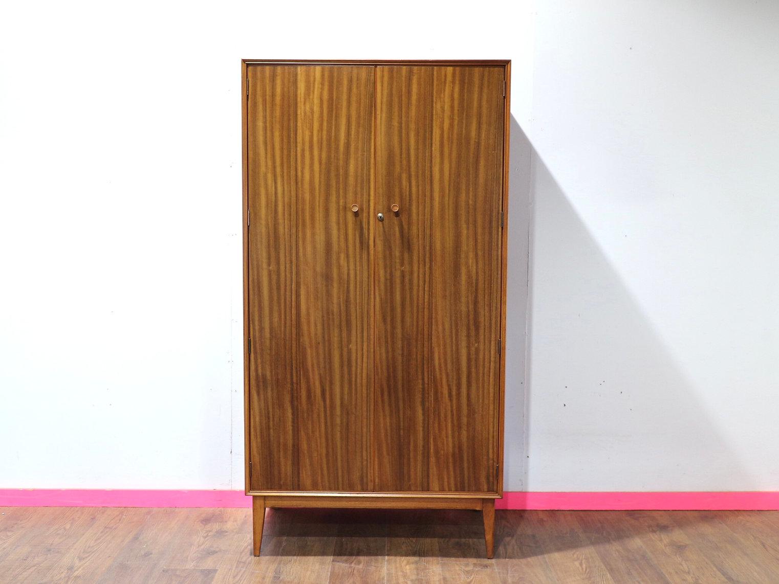 Rehaussez l'esthétique de votre chambre à coucher avec l'Armoire Vintage Moderne du Milieu du Siècle par Alfred COX, disponible chez Mid Century Traders. Cette grande armoire du milieu du siècle, méticuleusement fabriquée en noyer, offre un grand