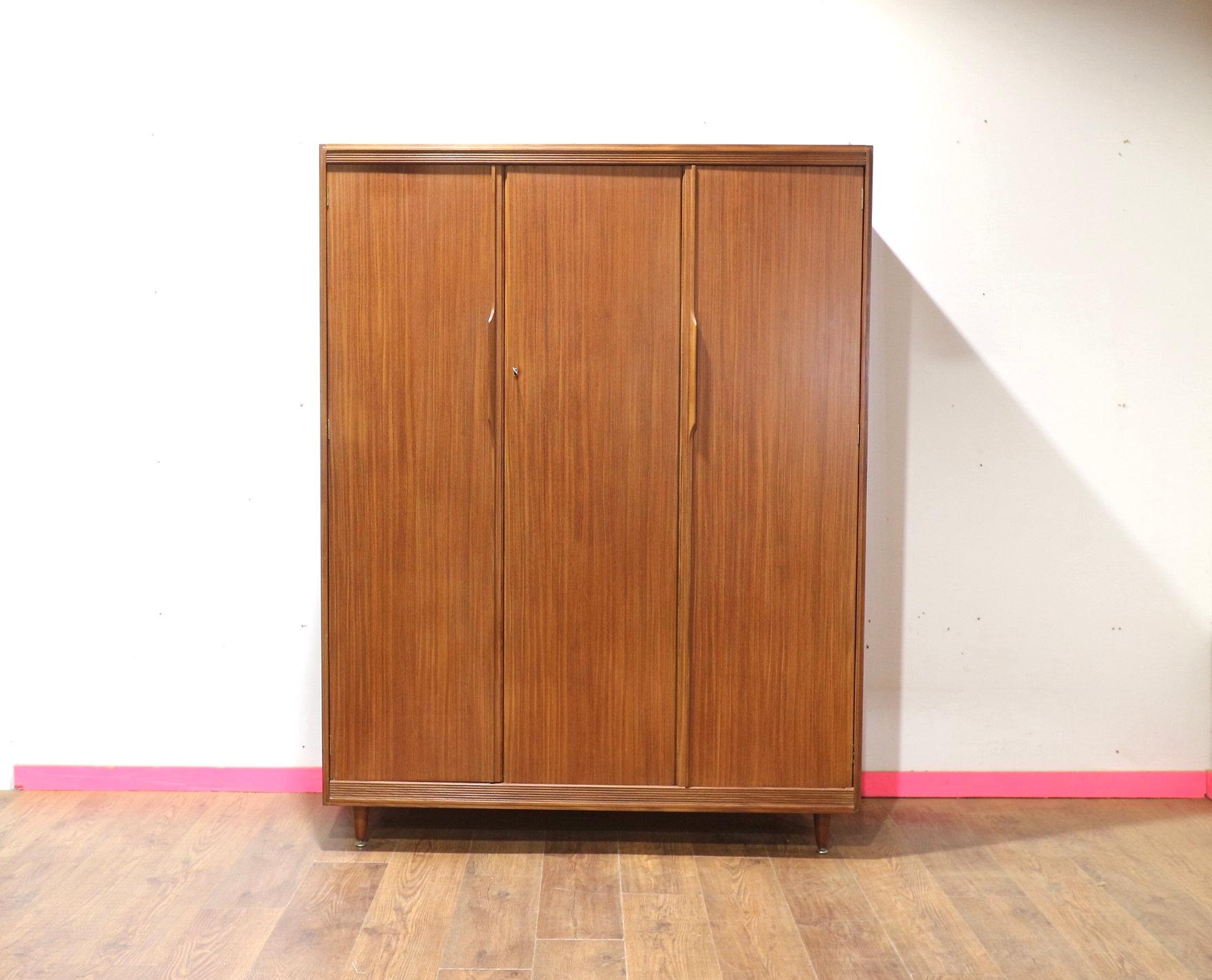 Descubre el encanto de la elegancia de mediados de siglo con este impresionante armario triple vintage del famoso fabricante de muebles británico White & Newton. Esta exquisita pieza ofrece amplio espacio para colgar y almacenamiento en estantes,