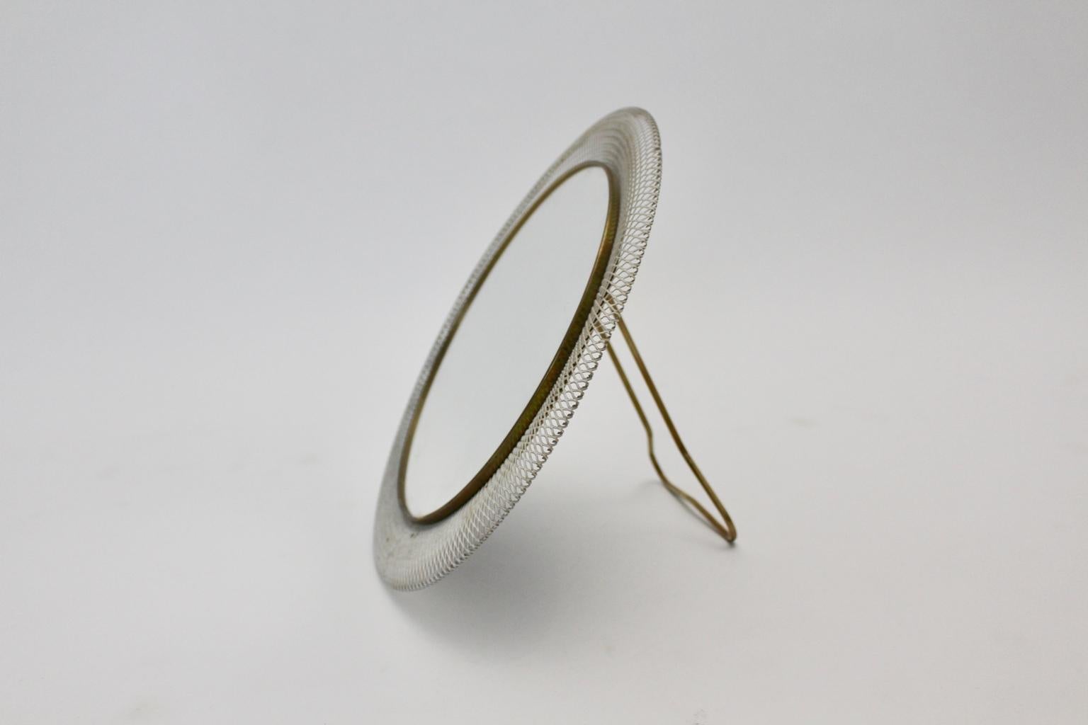 Miroir de table vintage de forme ronde datant du milieu du siècle dernier, attribué à Vereinigte Münchner Werkstätten. Il présente un anneau en laiton et un cadre en métal laqué blanc perforé. 
L'état d'origine est le suivant  bon avec des signes