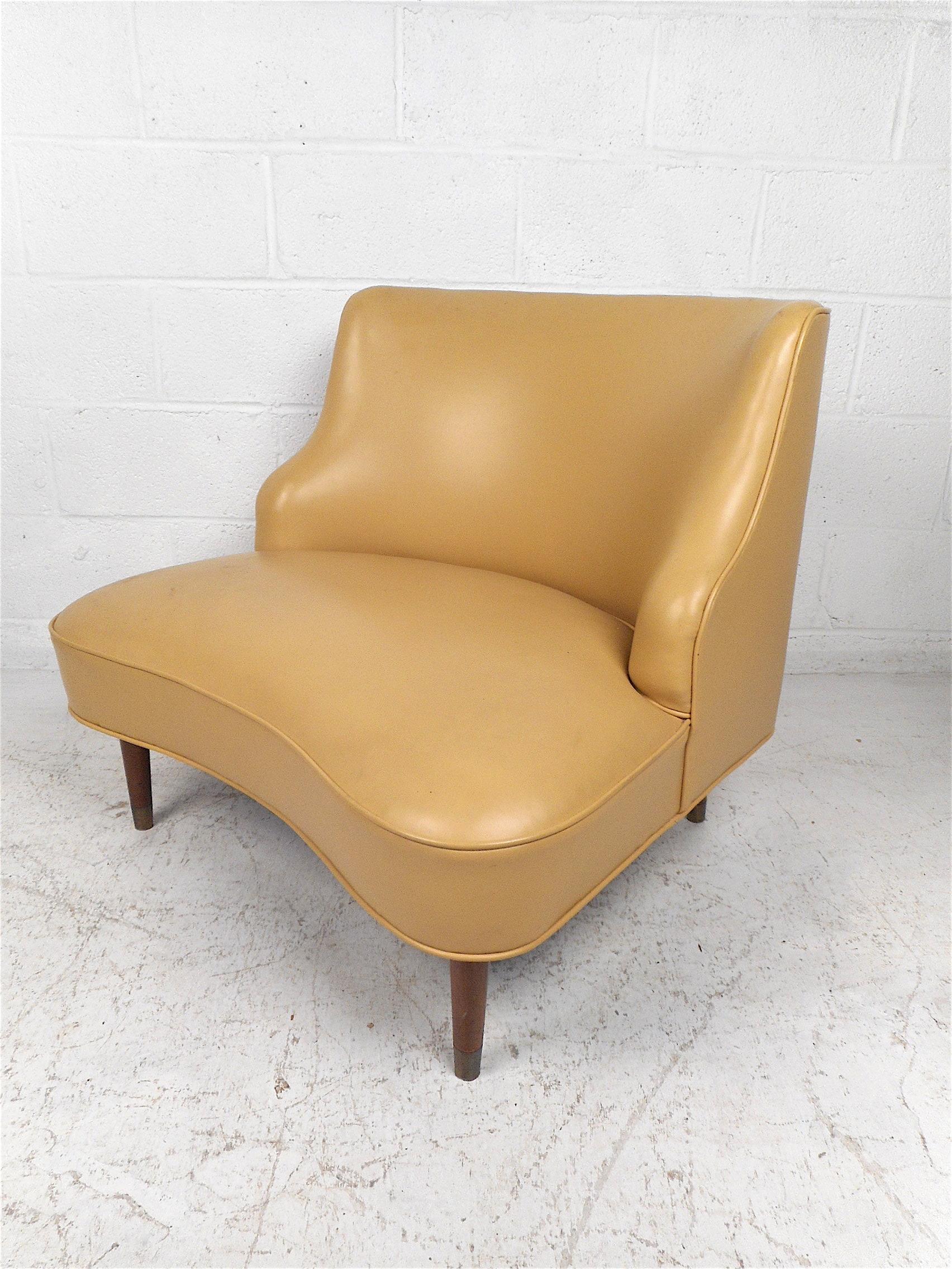 Mid-Century Modern vinyl lounge chair. Stylish chair featuring a wide spacious seating area, form-fitting backrest, and four tapered legs with sabots at their bottoms. Great chair sure to be an appropriate addition to any modern interior. Please