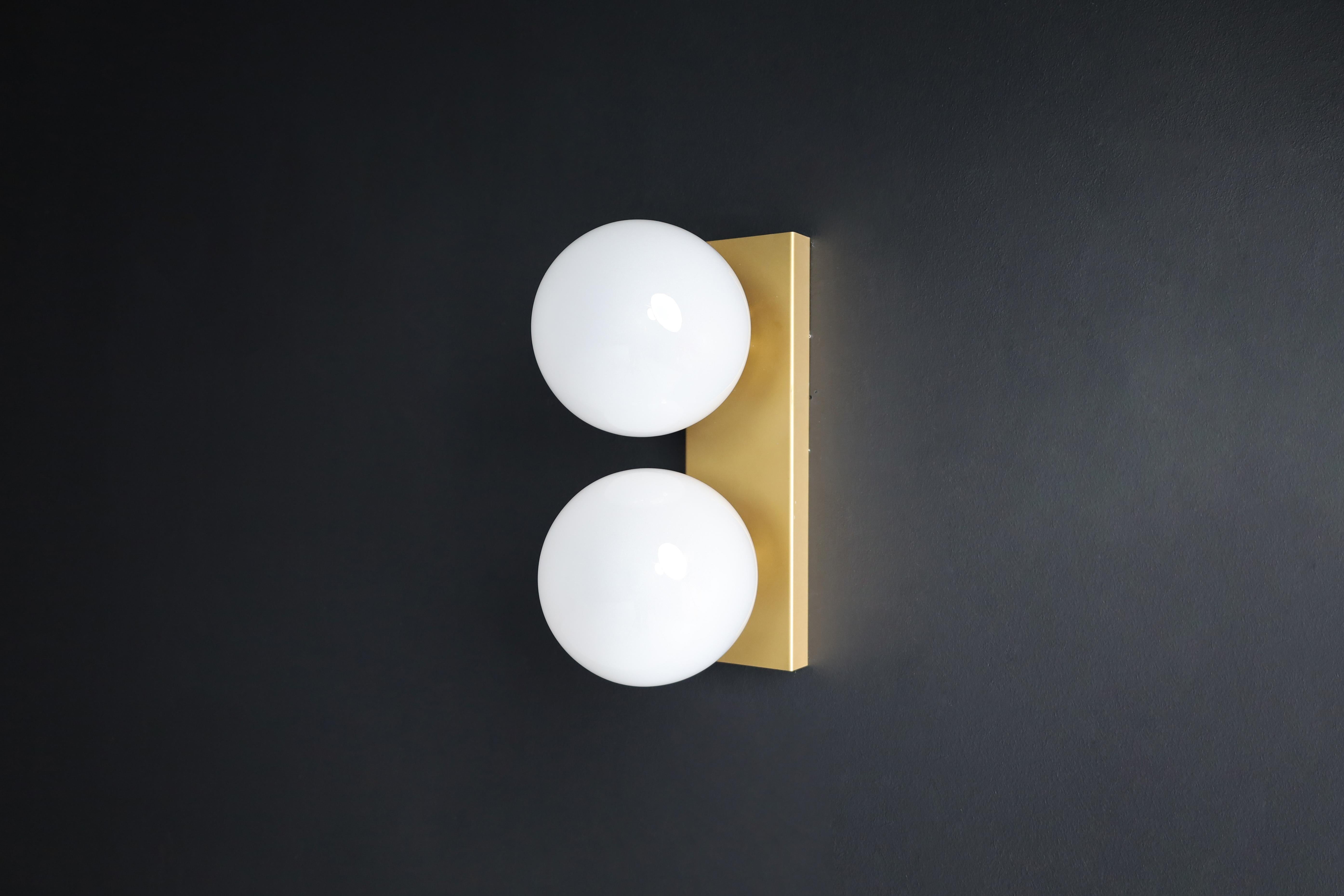Mid-20th Century wall/ceiling lights white frosted glass globes, 1960s

Double wall sconces / ceiling lights with rectangular brass backplates and hand blew frosted glass globes. The bulbs are connected directly to a brass vertical/horizontal slat