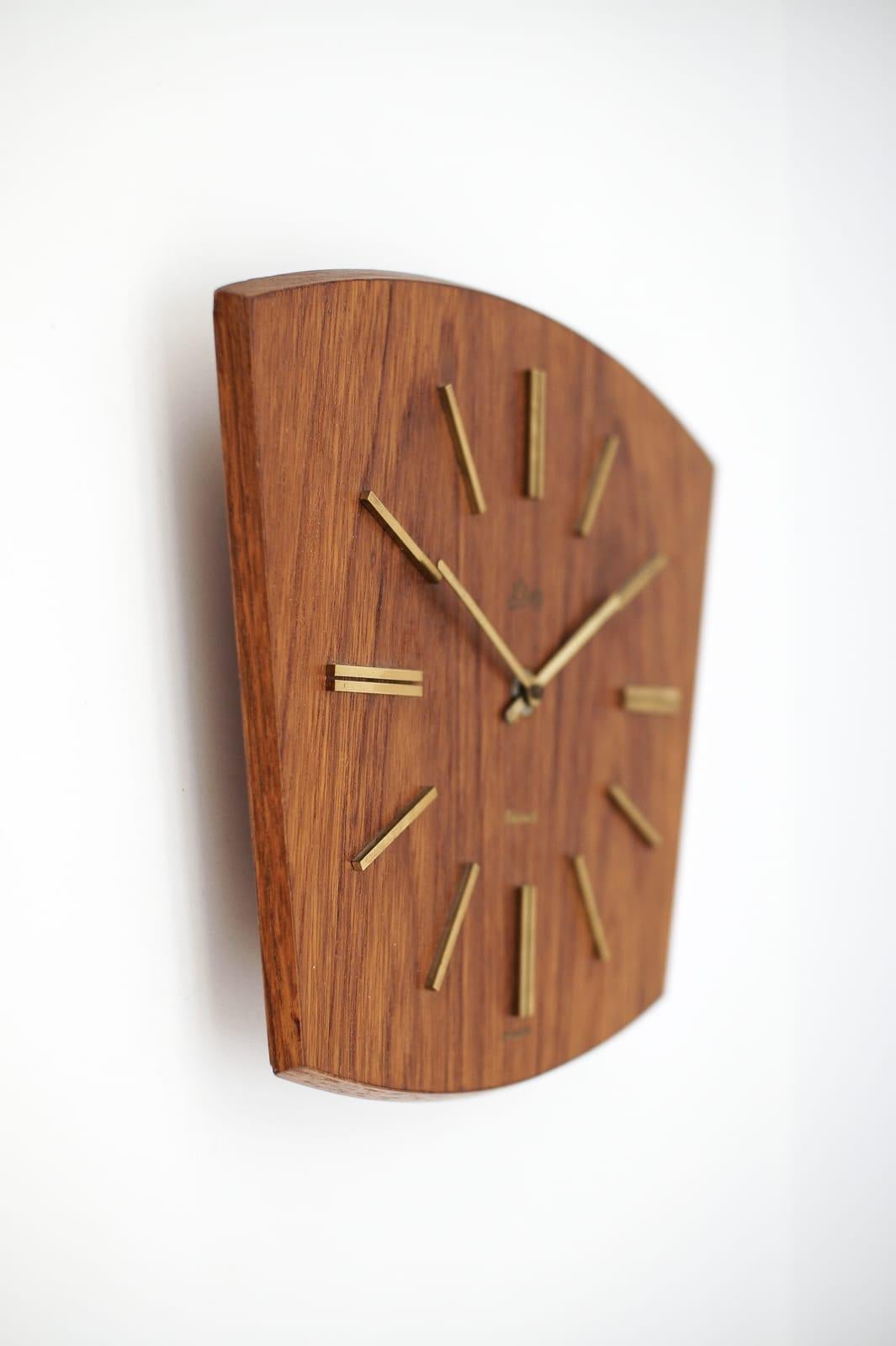Stunning wall clock made of teak and brass. 

One of the most beautiful models I have seen to date.

An eye catcher par excellence.

Made in Germany.

Electric, battery operated clock.