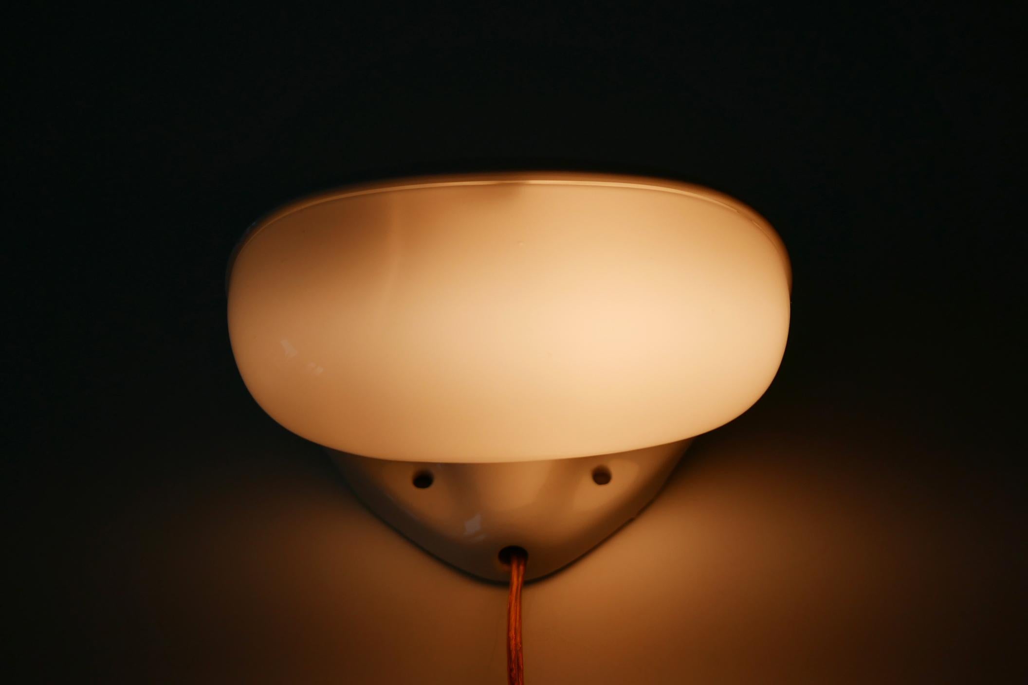 Elegant Mid-Century Modern mirror lamp or sconce. Modell number 348. Designed in 1956 by the famous German designer Wilhelm Wagenfeld. Manufactured by Lindner GmbH in 1950s-1960s, Germany.

Executed in glazed white ceramic and opaline glass, it