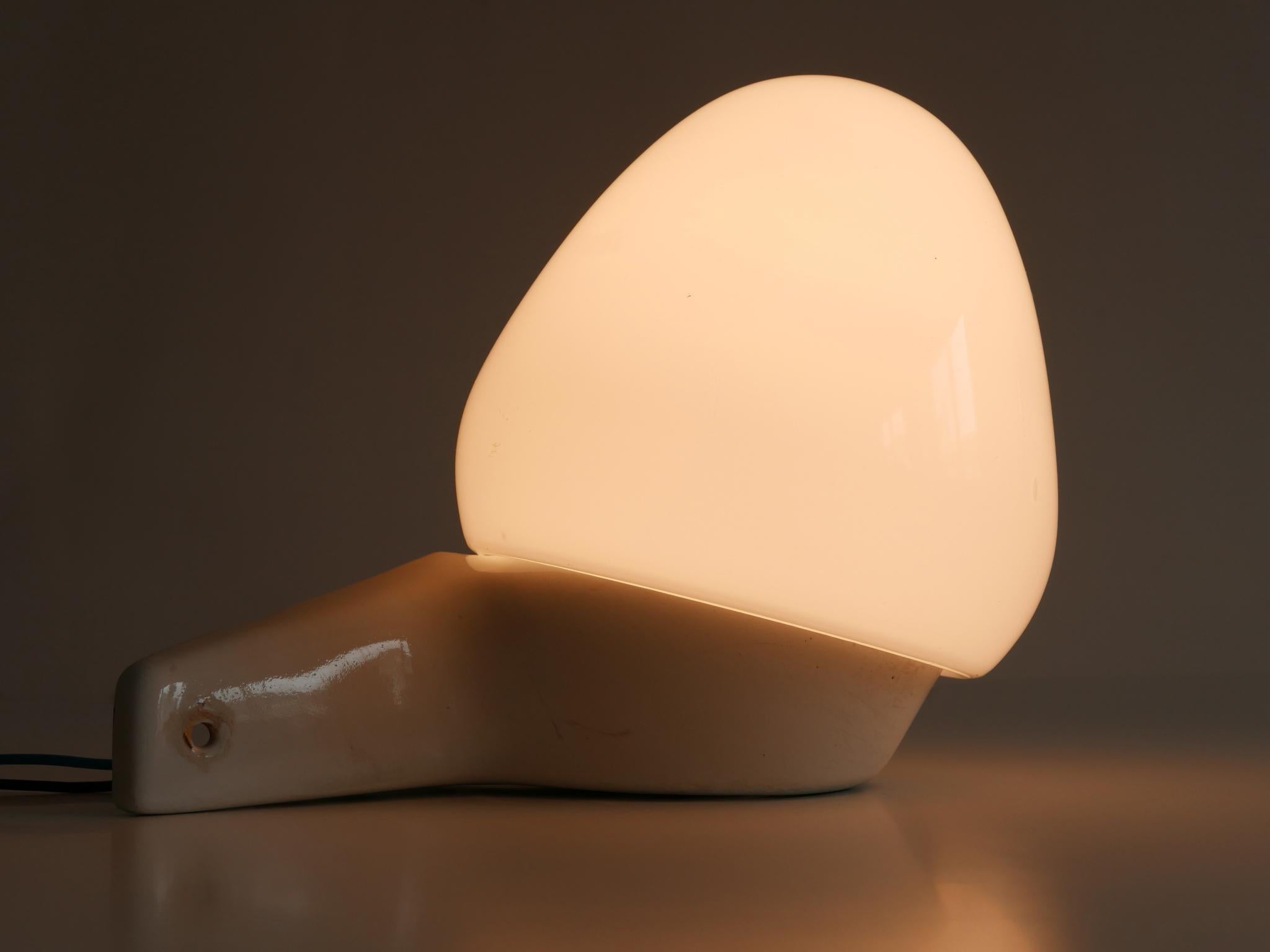 Elegant Mid-Century Modern corner wall light or sconce. Designed in 1950s by the famous German designer Wilhelm Wagenfeld. Manufactured by Lindner GmbH, Germany, 1950s.

Executed in glazed white ceramic and opaline glass, it comes with 1 x E27 / E26