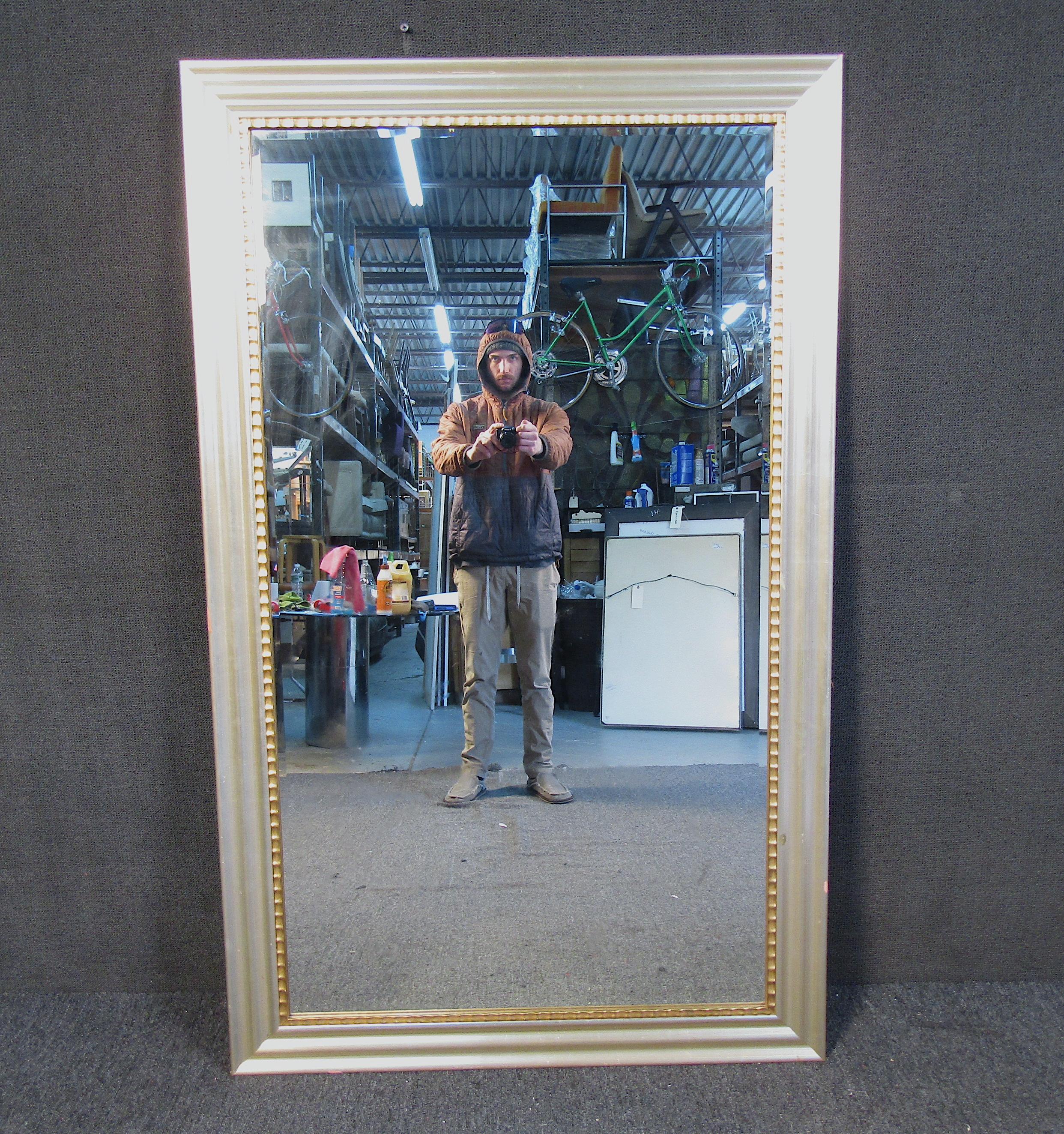 This elegant mid-century style mirror features a sloped silver frame with ribbed accenting. A perfect addition to any open wall space in need of a mirror. Please confirm item location (NY or NJ).