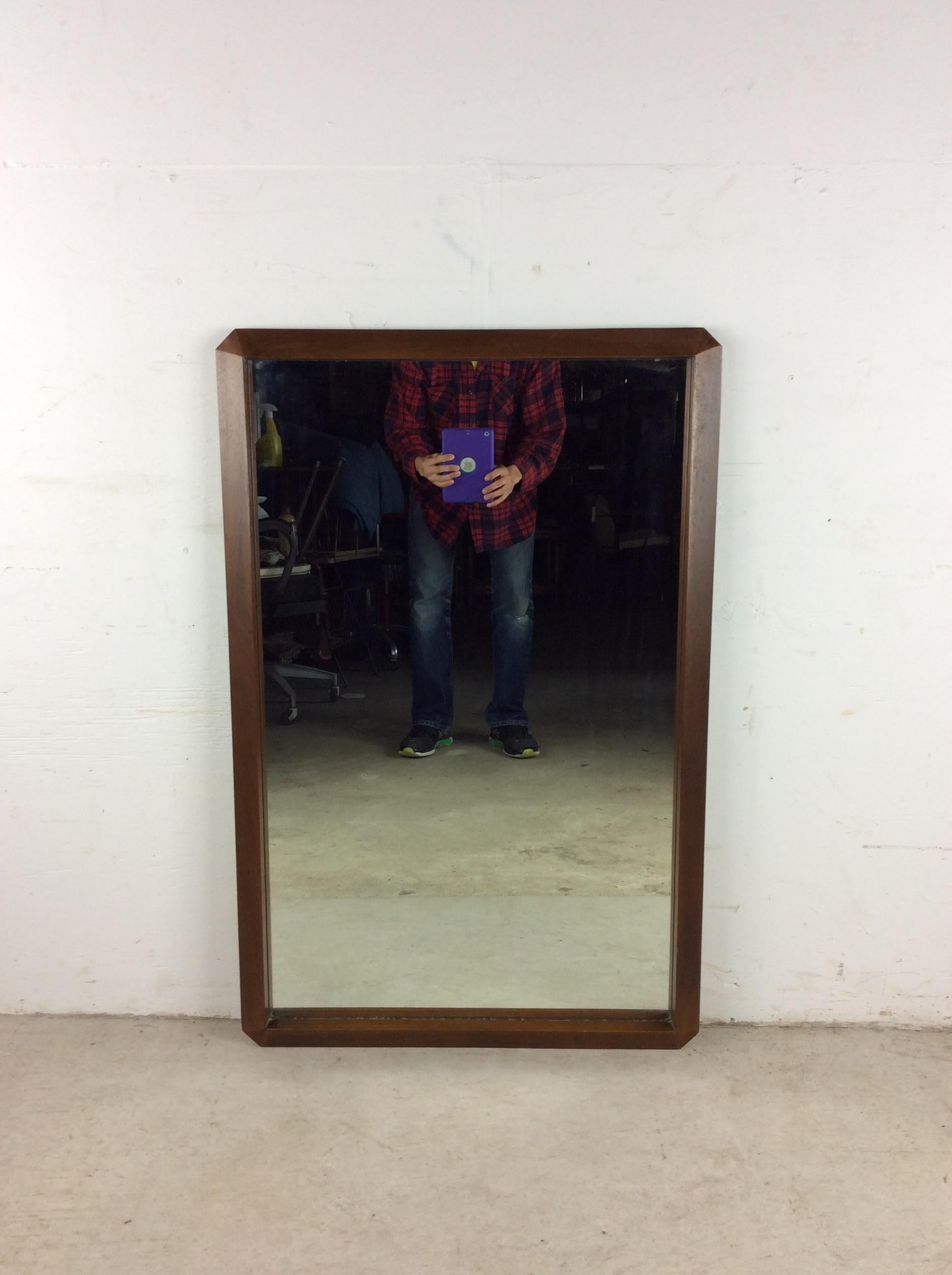 This mid century modern mirror features hardwood frame, original walnut finish, angular frame, and partial mounting hardware. 

Dimensions: 27w 1.75d 41h

Condition: Wood frame and finish are in excellent condition.  The mirrored glass is also very