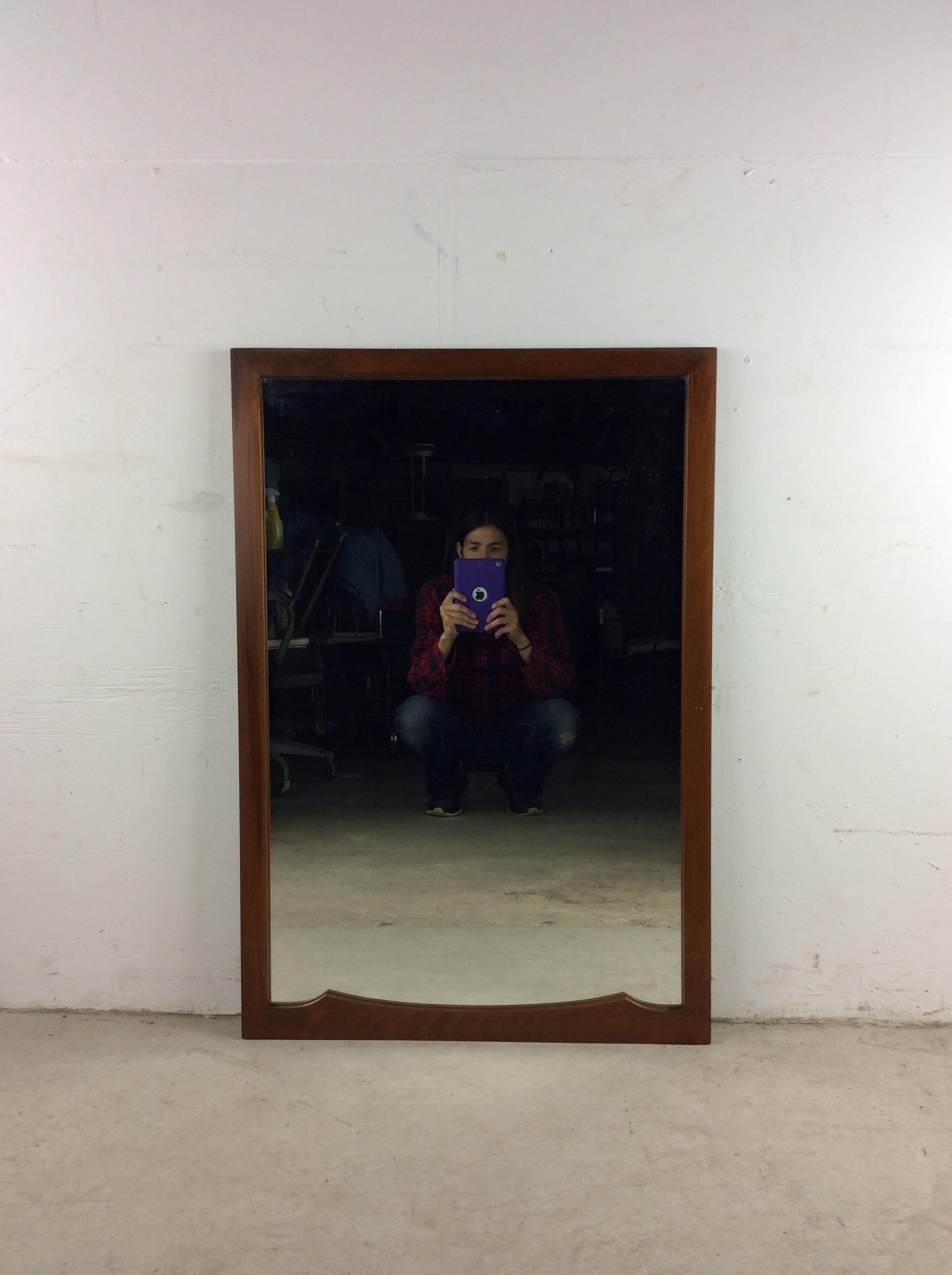 This mid century modern mirror features hardwood frame, original walnut finish, rectangular frame with two little curved accent pieces at the bottom, and partial mounting hardware. 

Dimensions: 26.5w 1d 38.5h

Condition: Wood frame and finish are